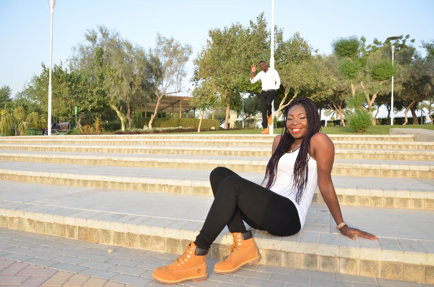 Person wearing casual outfit sits on concrete steps outdoors.