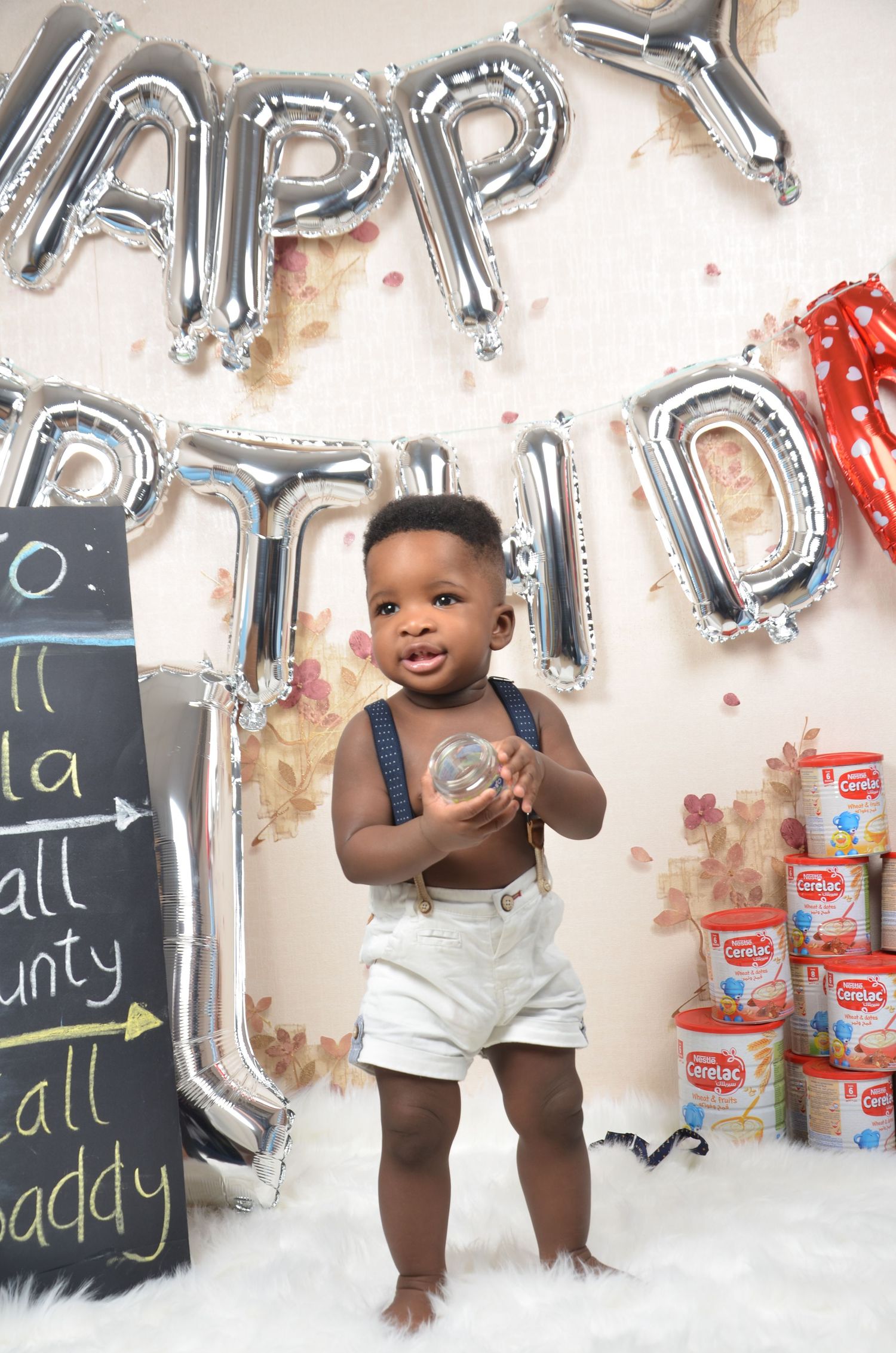 Birthday party scene with silver balloon letters, chalkboards, and festive decorations.