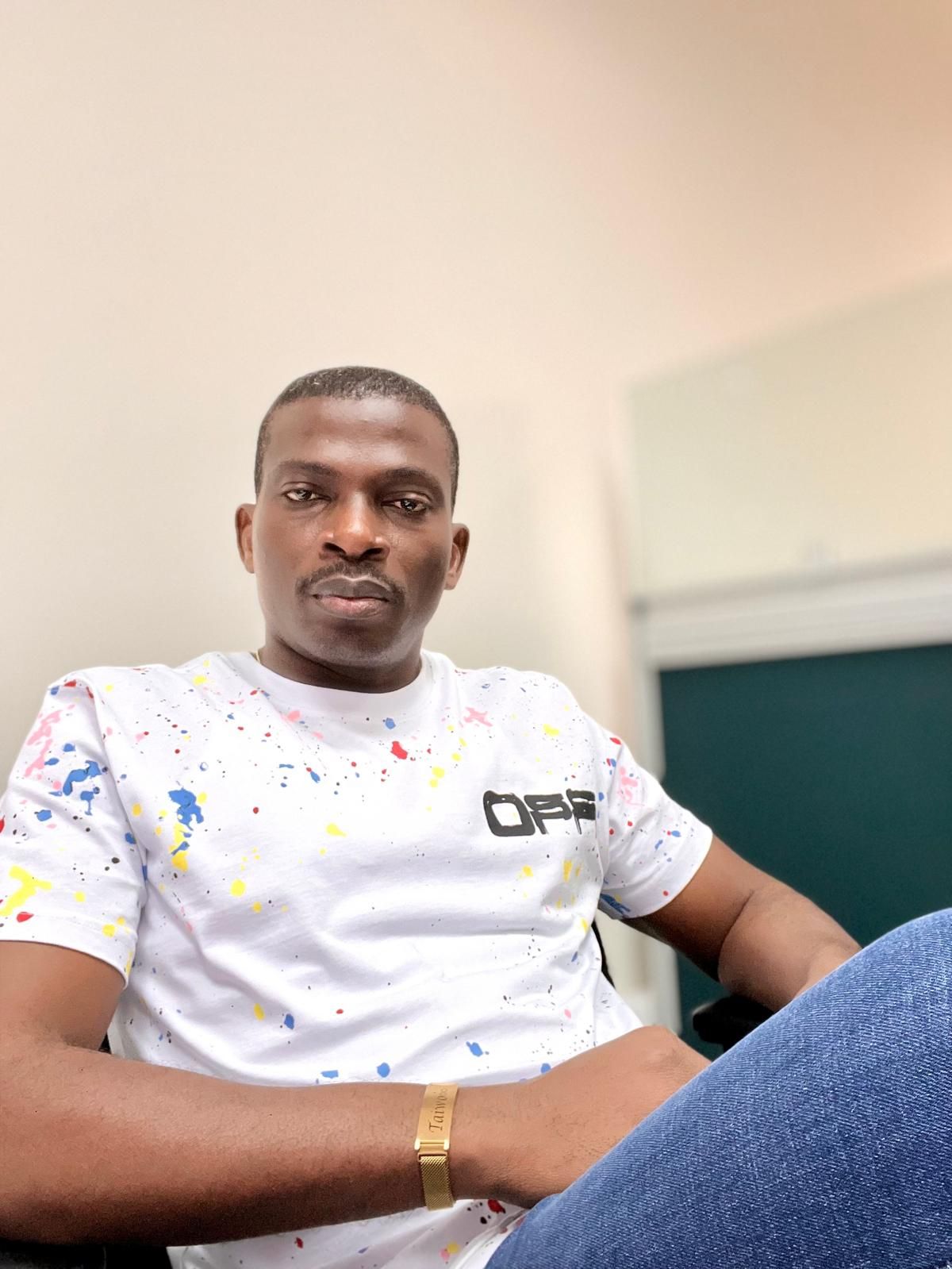 Casual portrait in white paint splatter t-shirt and jeans with gold watch.