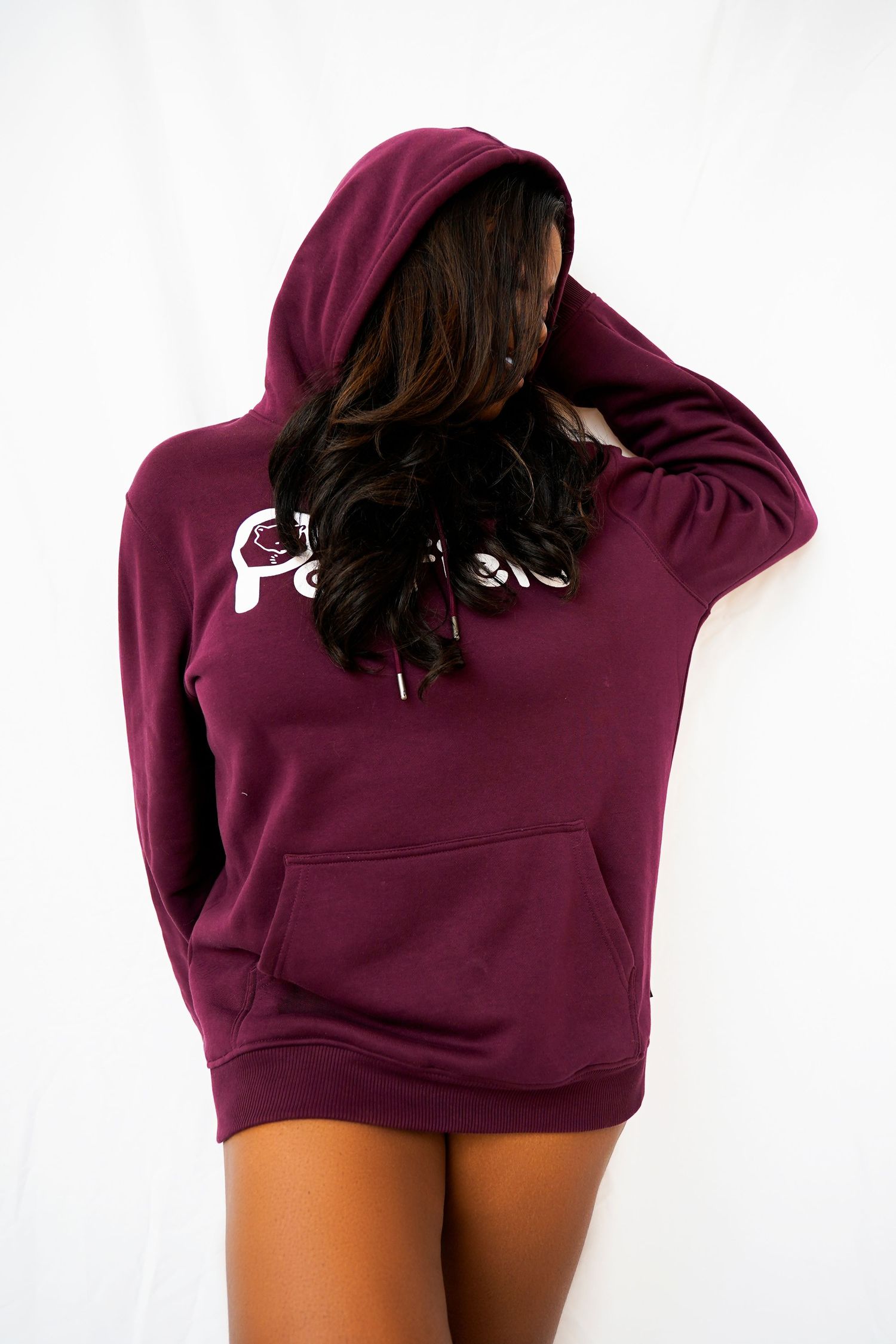 Person wearing burgundy hoodie poses seductively against white background.