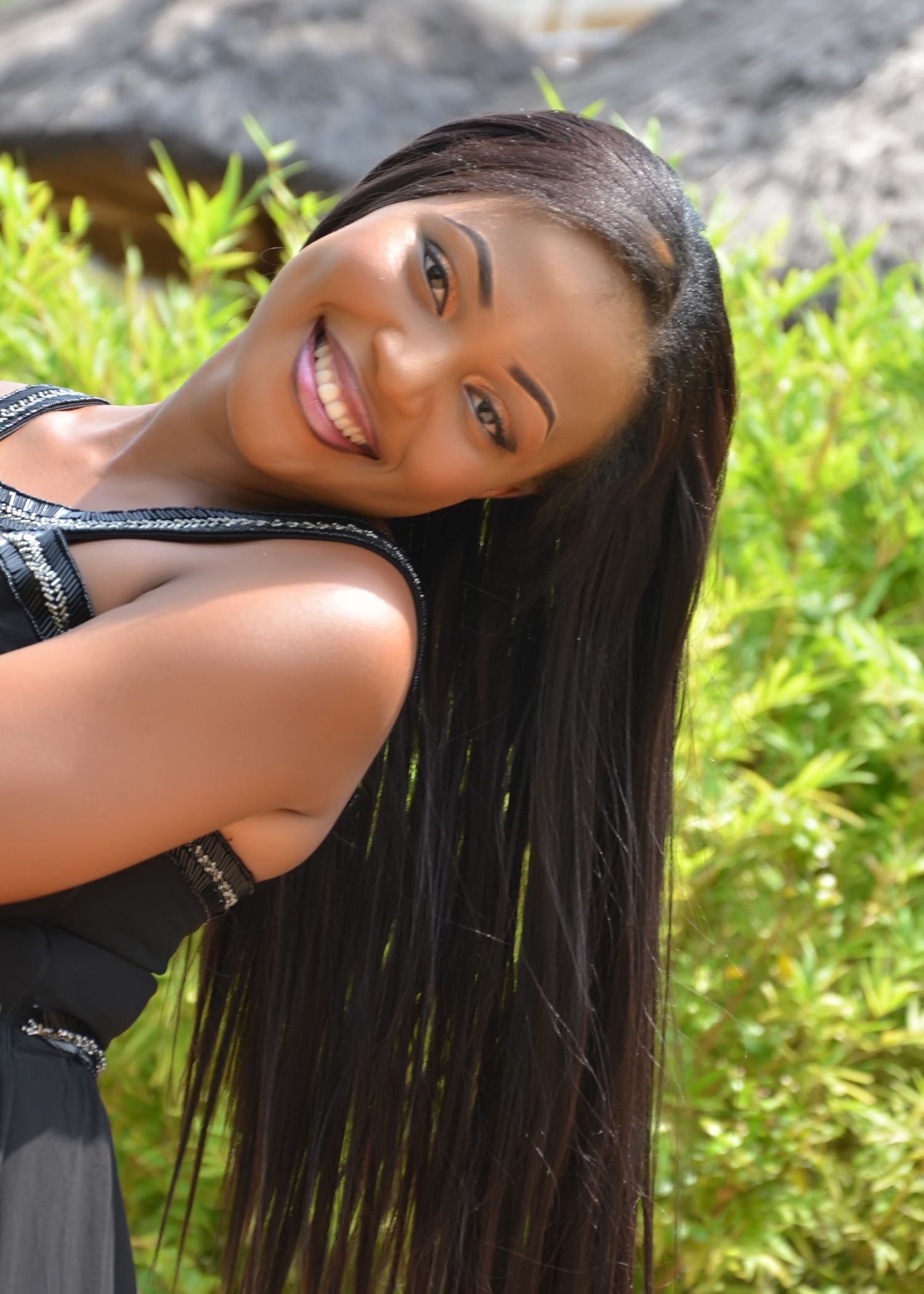 Close-up outdoor portraits with long dark hair against sunlit garden foliage.