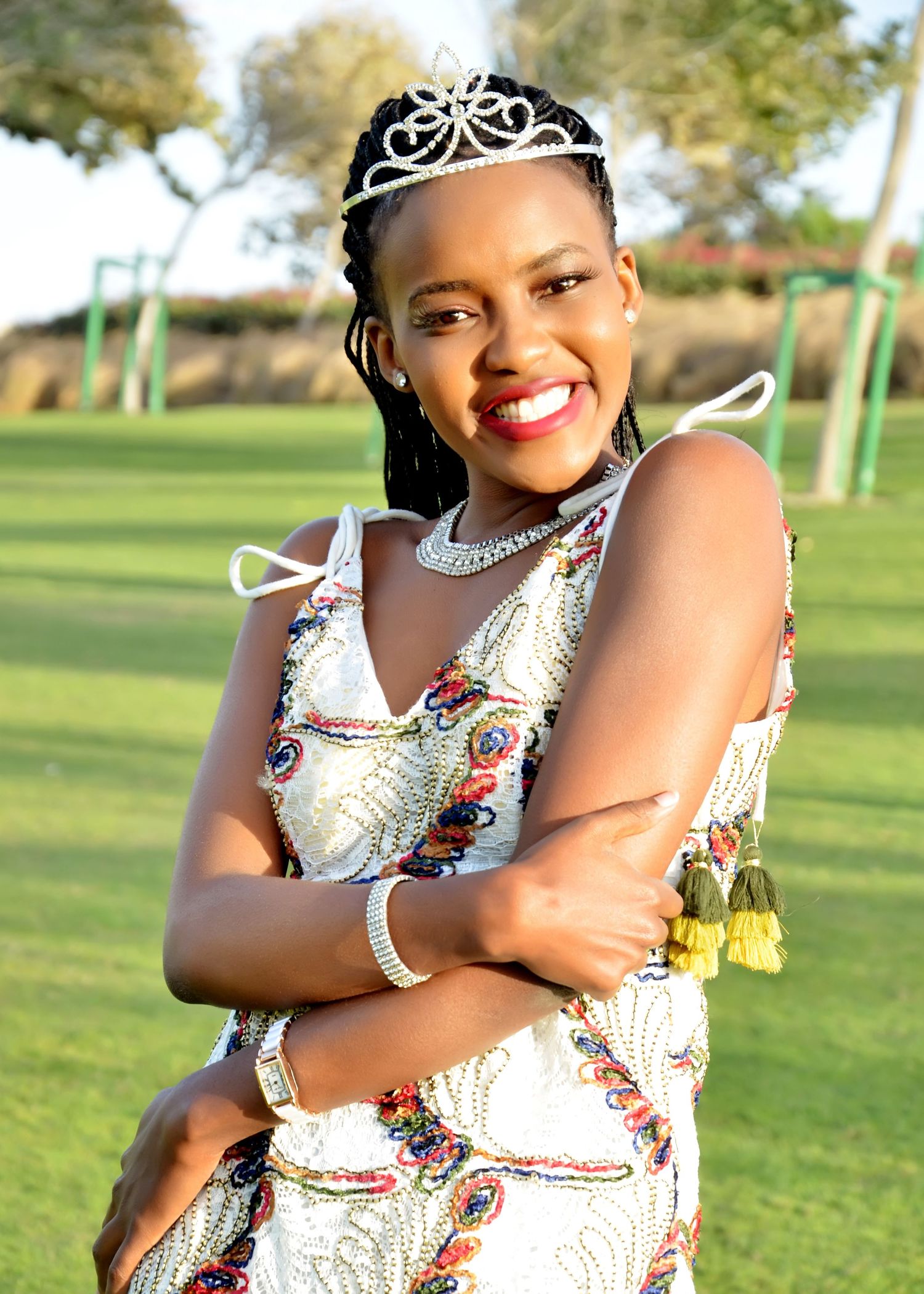 A sparkly tiara crowns a festive outdoor photoshoot on a sunny golf course.