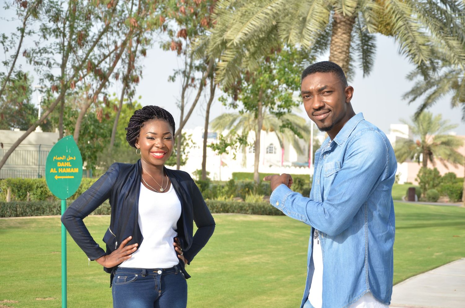 Two people walk together on palm-lined path wearing casual outfits.