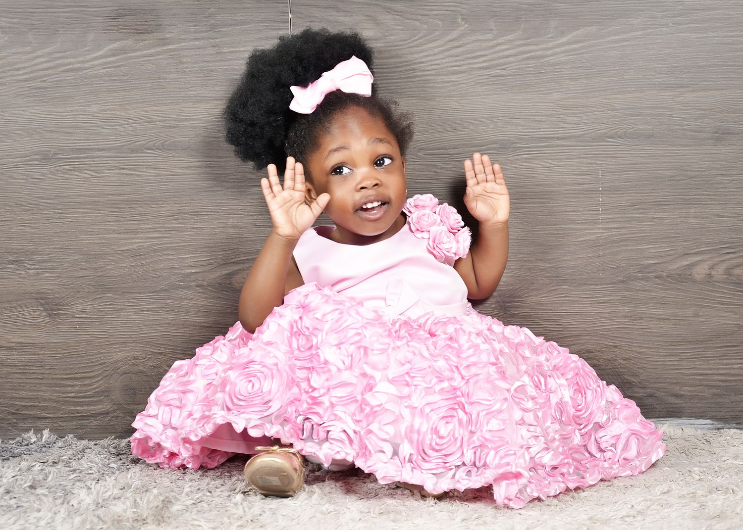 A festive photo with a pink ruffled dress against a grey background.