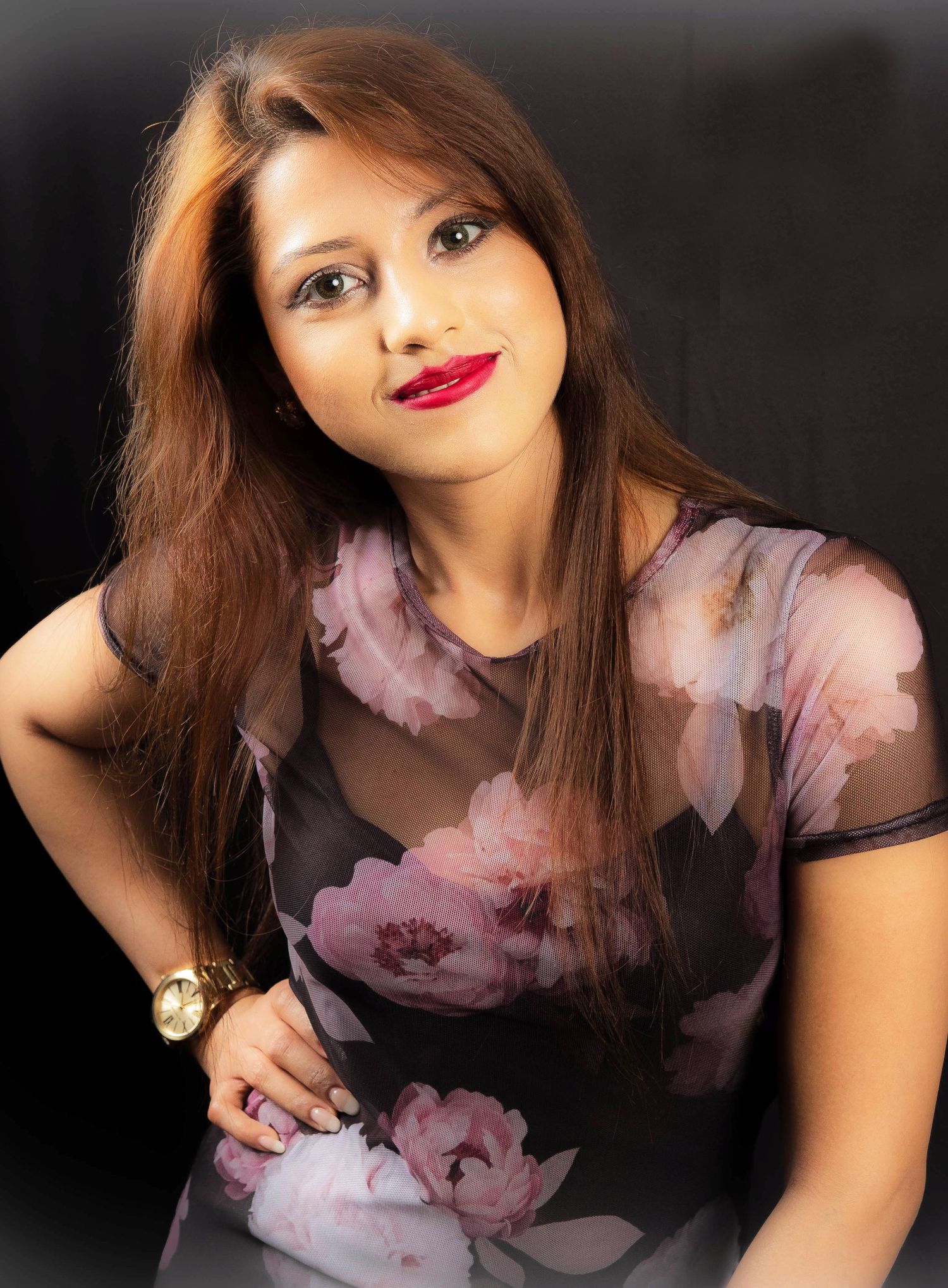 Fashion portrait featuring a floral pink blouse against dark background in dramatic lighting.