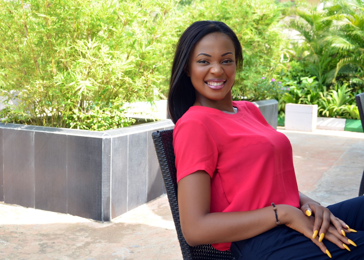 Woman in red t-shirt sits relaxed in outdoor patio setting with modern decor.
