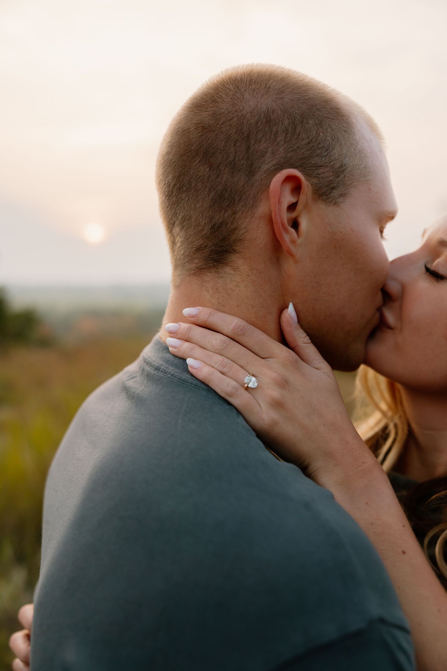 A close-up of an intimate kiss at sunset showing an engagement ring. sioux falls photographer riley ro photo