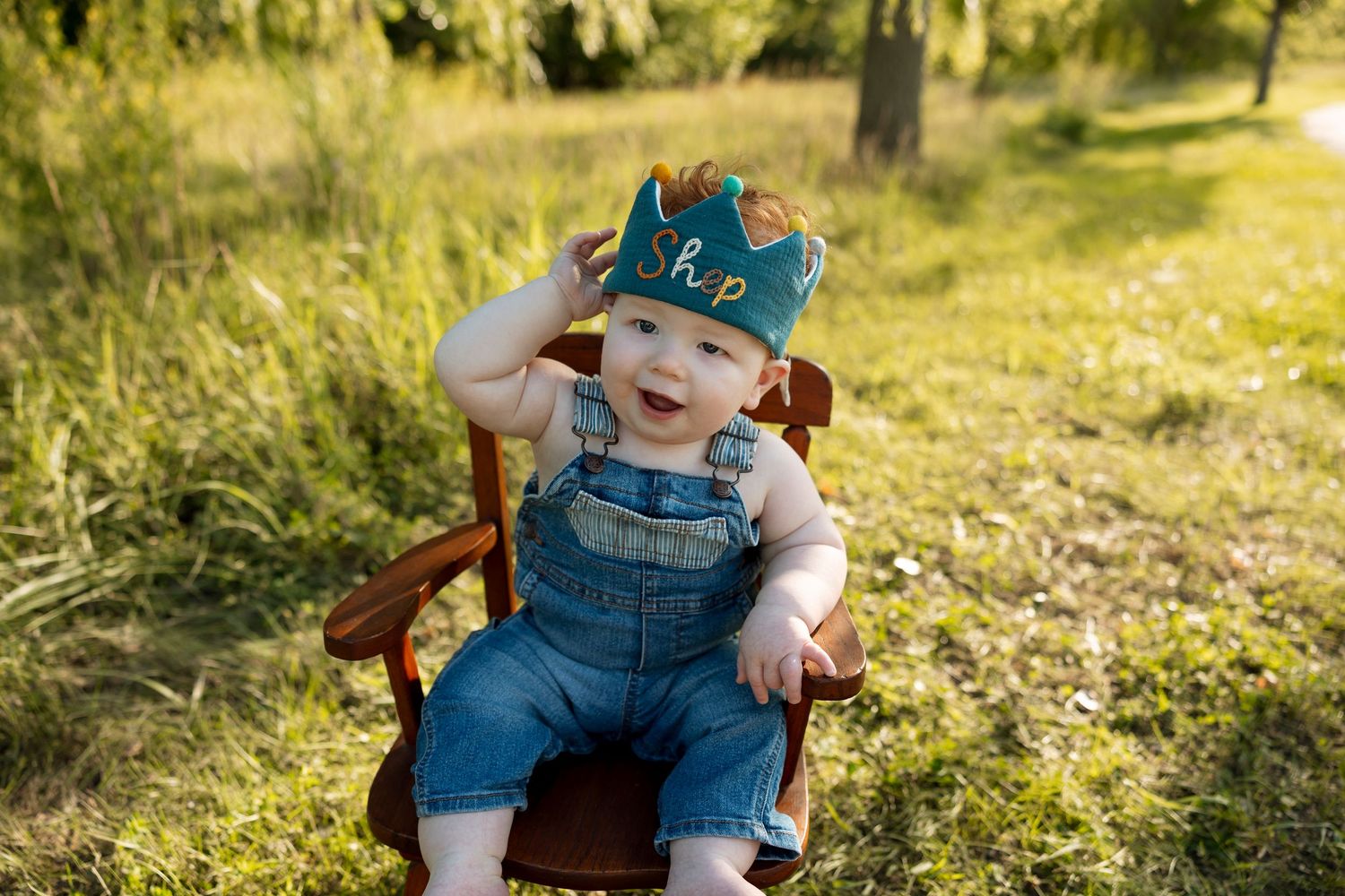 A child wearing denim overalls plays in a sunny garden during golden hour.