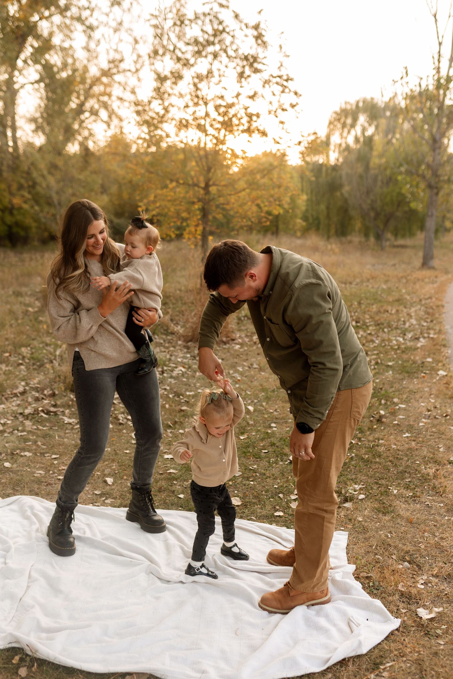 Family shares playful moment together on white blanket during golden hour autumn photoshoot in nature. Riley Ro Photo Sioux Falls, SD