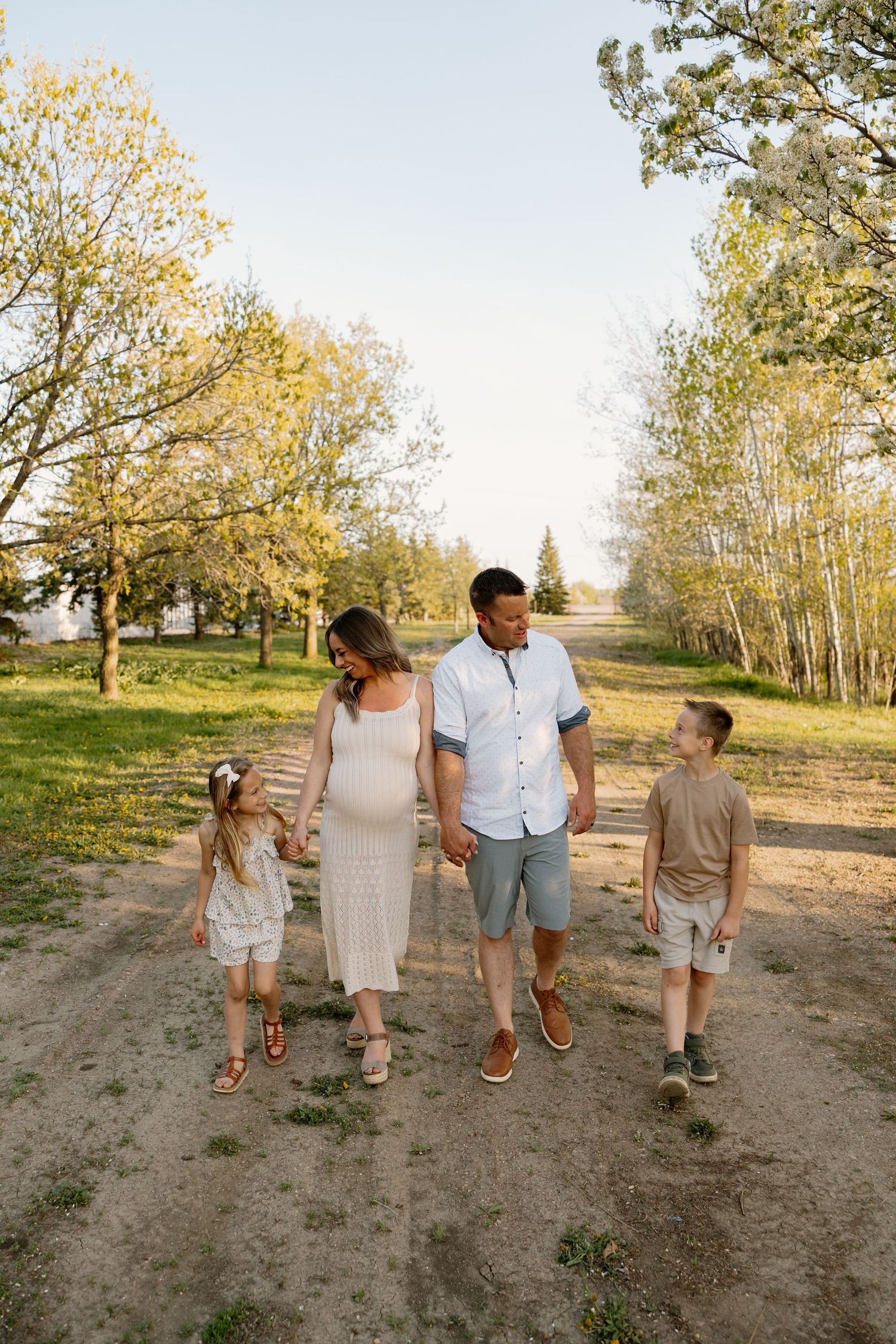 A family walks together down a dirt path surrounded by autumn trees on a sunny afternoon.
