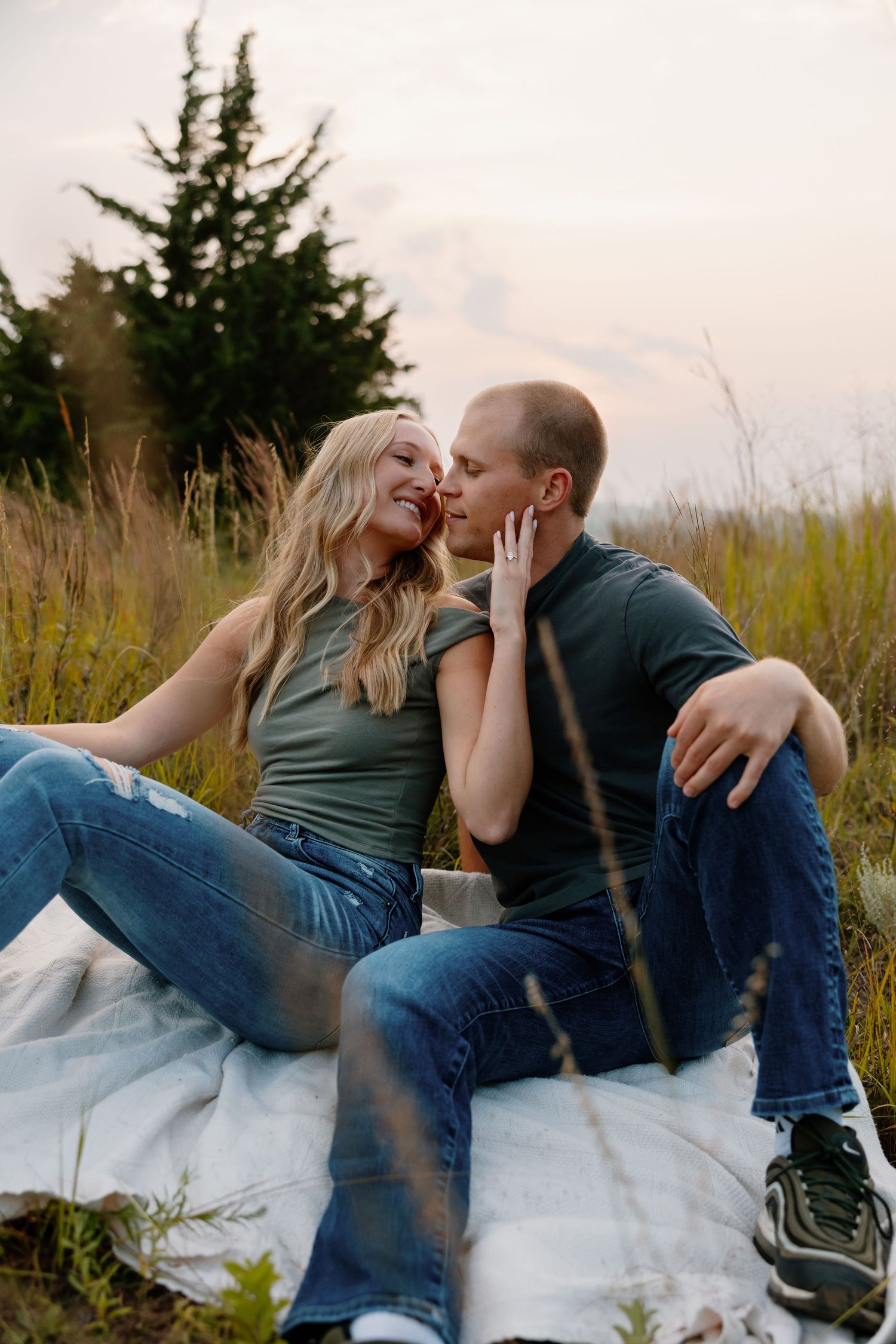 A couple sharing an intimate moment while sitting on a blanket in tall grass. sioux falls photographer riley ro photo