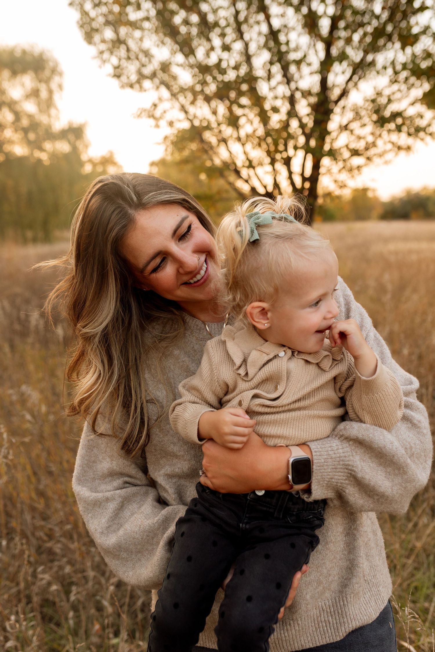 A parent and child share joyful laughter while playing together in a golden sunlit field at sunset. Riley Ro Photo Sioux Falls, SD