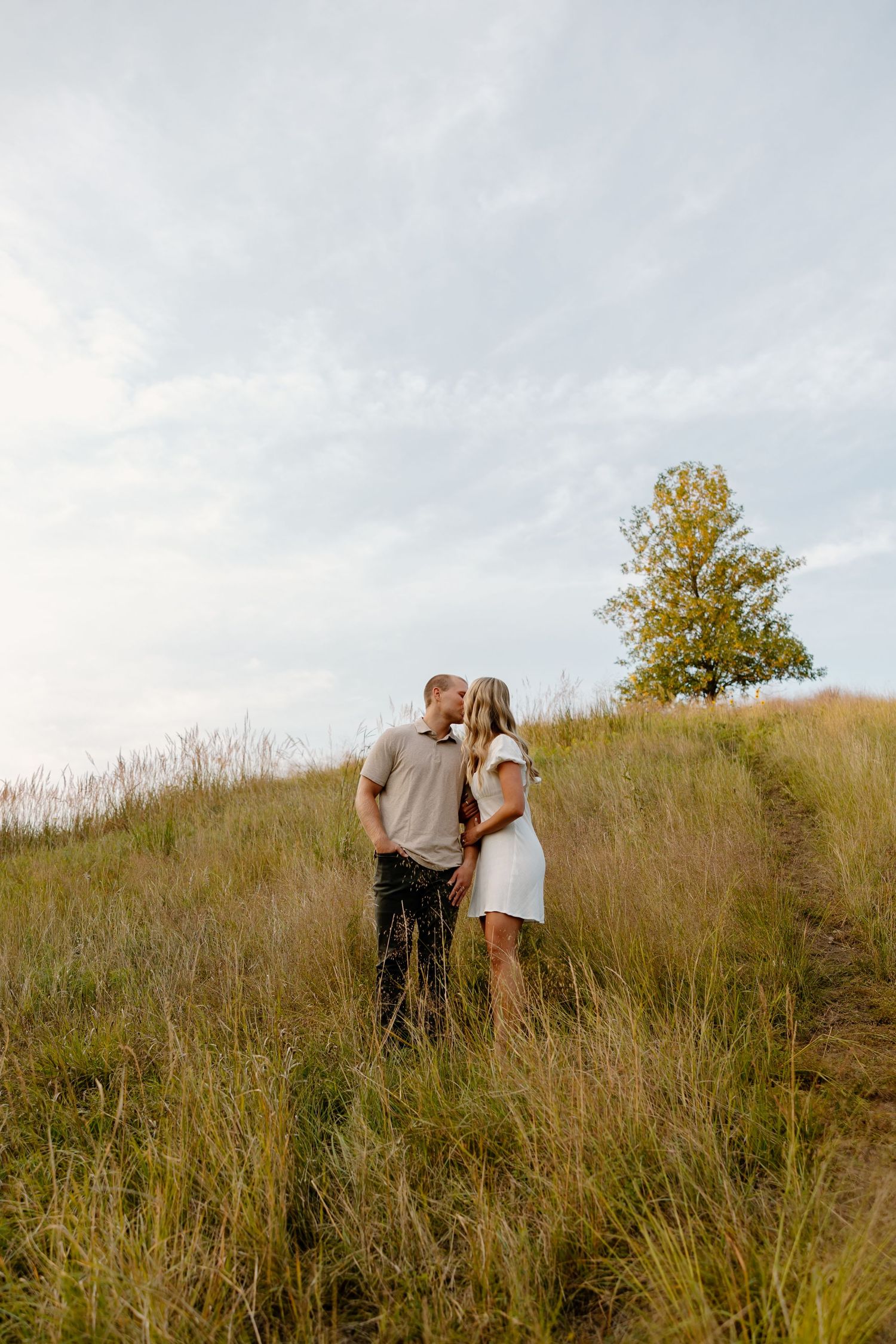 Intimate moment shared between a couple on a scenic hilltop during golden hour.