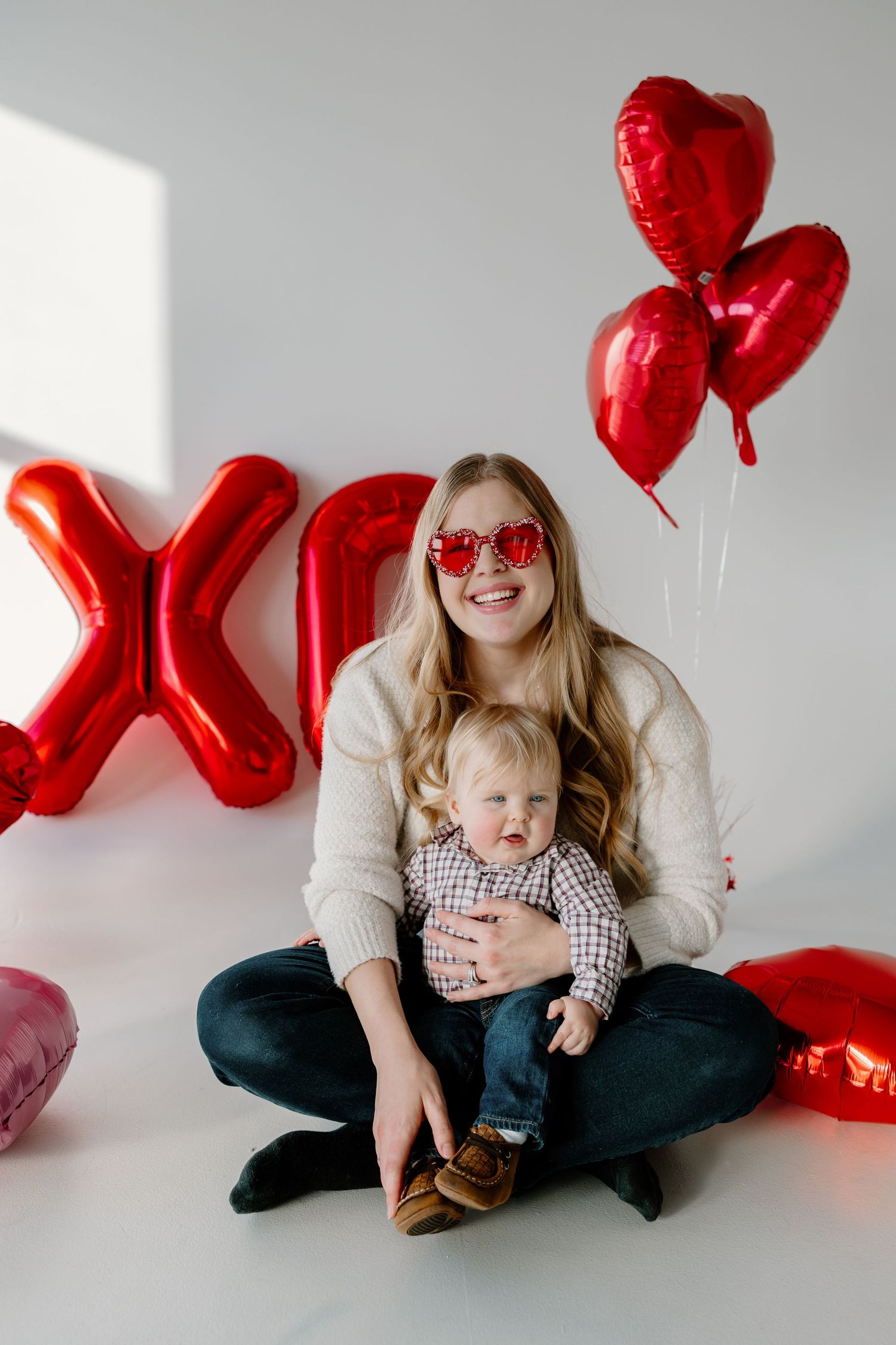 Valentine's Day themed photo with red heart balloons, decorative X, and heartwarming parent-child moment.