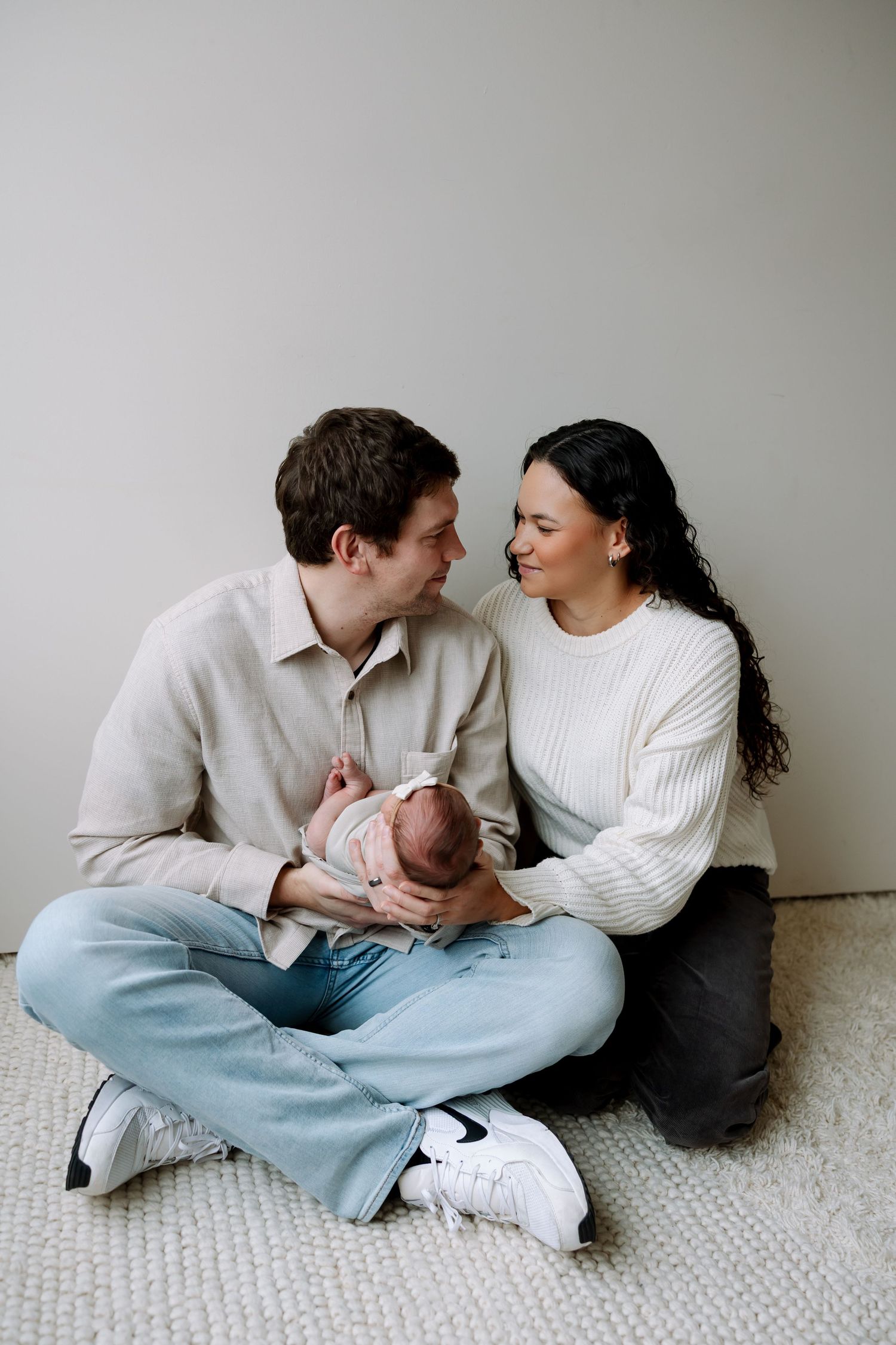 Couple in white and casual attire sitting on carpet sharing intimate moments in sequence of romantic poses.