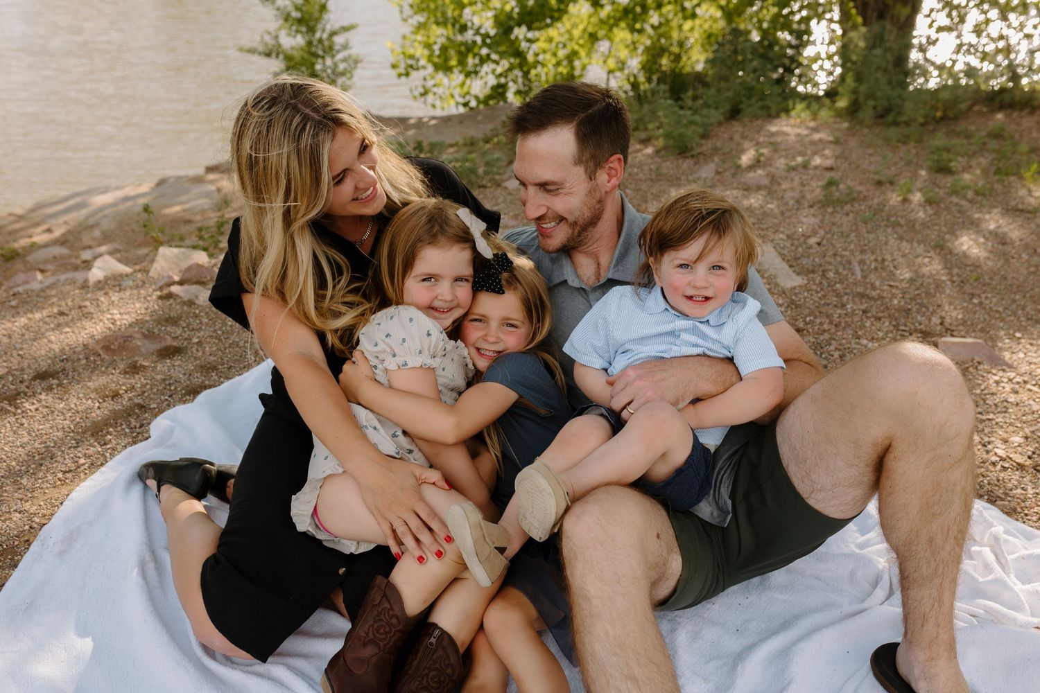Family members share tender moments together while relaxing outdoors in casual clothing.