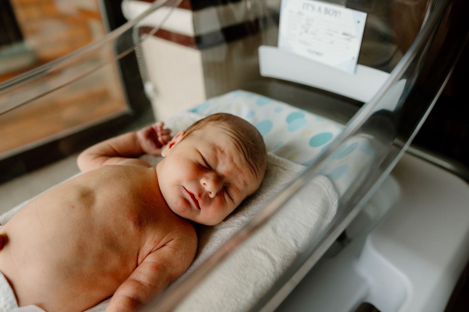 A newborn baby lies on a medical bassinet during a hospital examination.