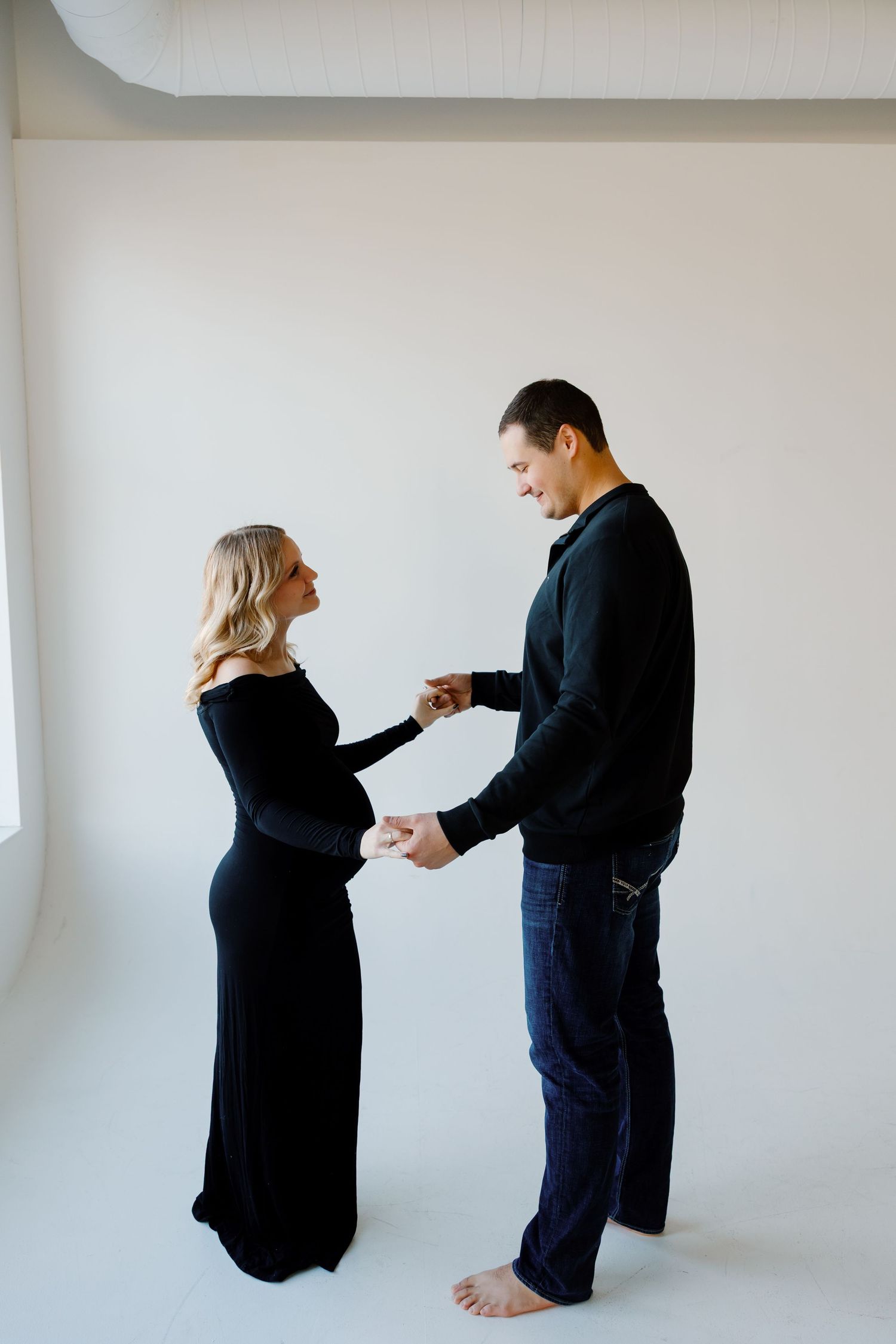 A couple shares a playful moment during their maternity photoshoot in a studio setting. Riley Ro Photo Sioux Falls, SD