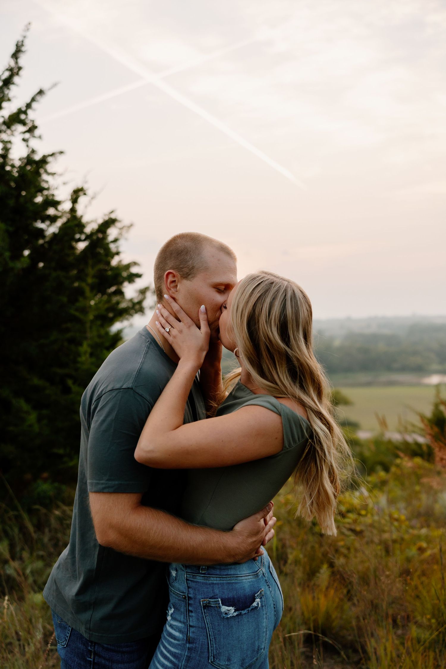 A tender moment between a couple embracing against a sunset sky background. sioux falls photographer riley ro photo
