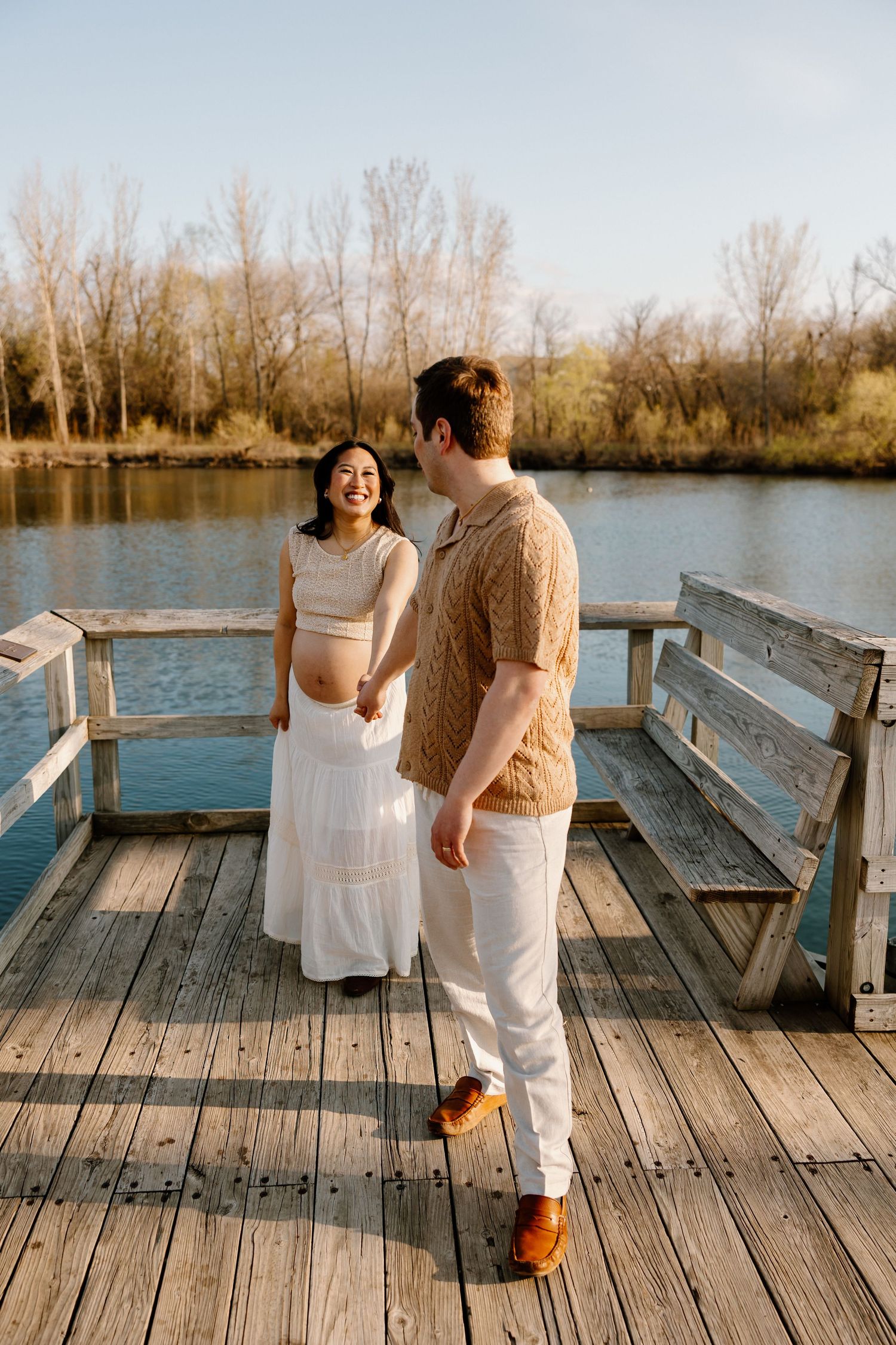 A couple shares a romantic moment on a wooden dock by a lake during golden hour.