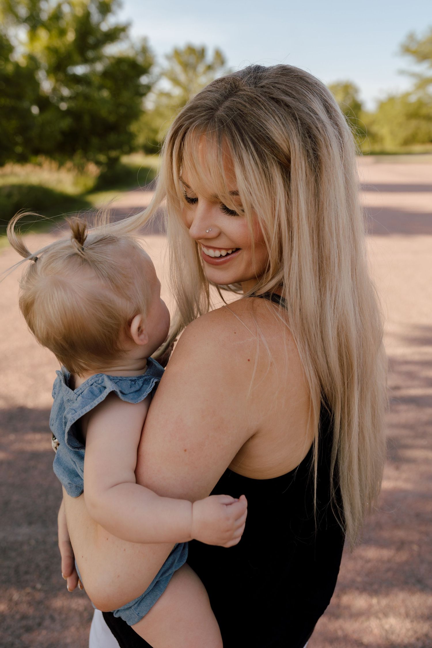 Sweet bonding moment between parent and baby captured in warm natural lighting on a pathway.