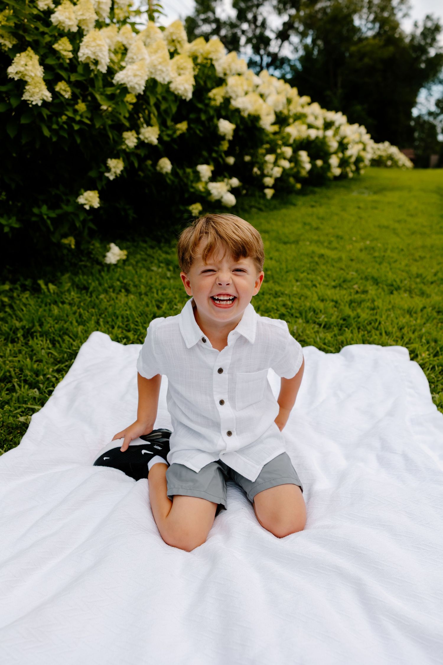 A series of outdoor portrait shots on white fabric against green grass with yellow flowers in the background. Riley Ro Photo Sioux Falls, SD