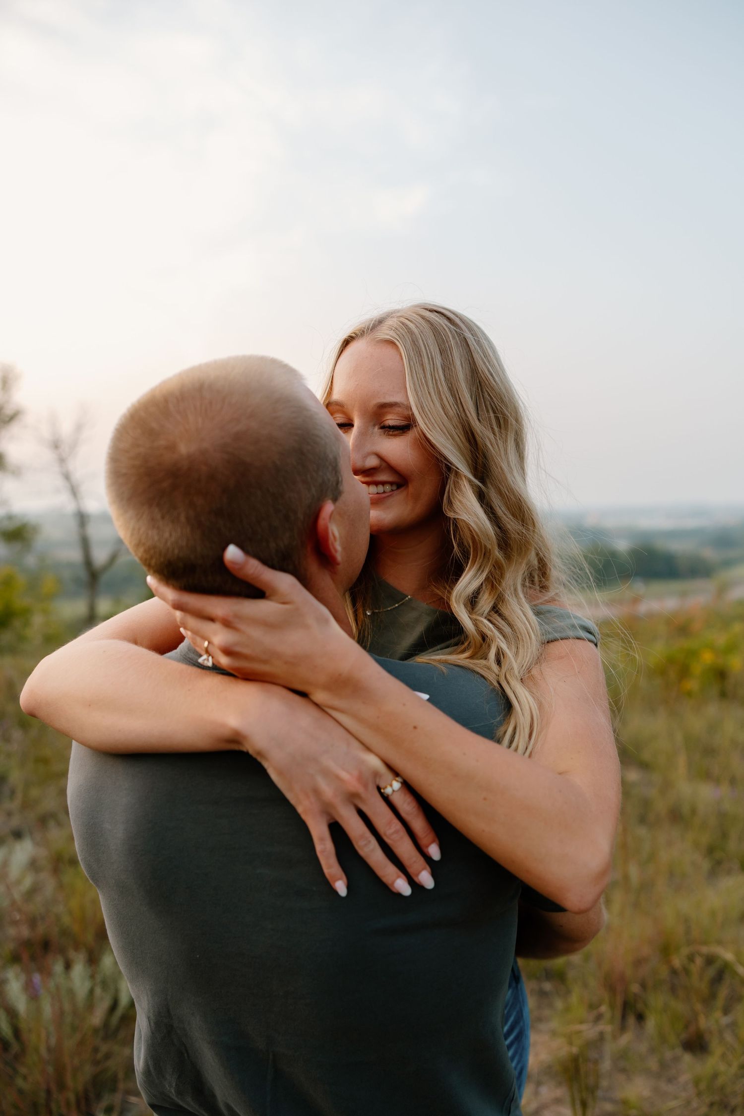 A close intimate embrace between a couple with a sparkling engagement ring visible. sioux falls photographer riley ro photo