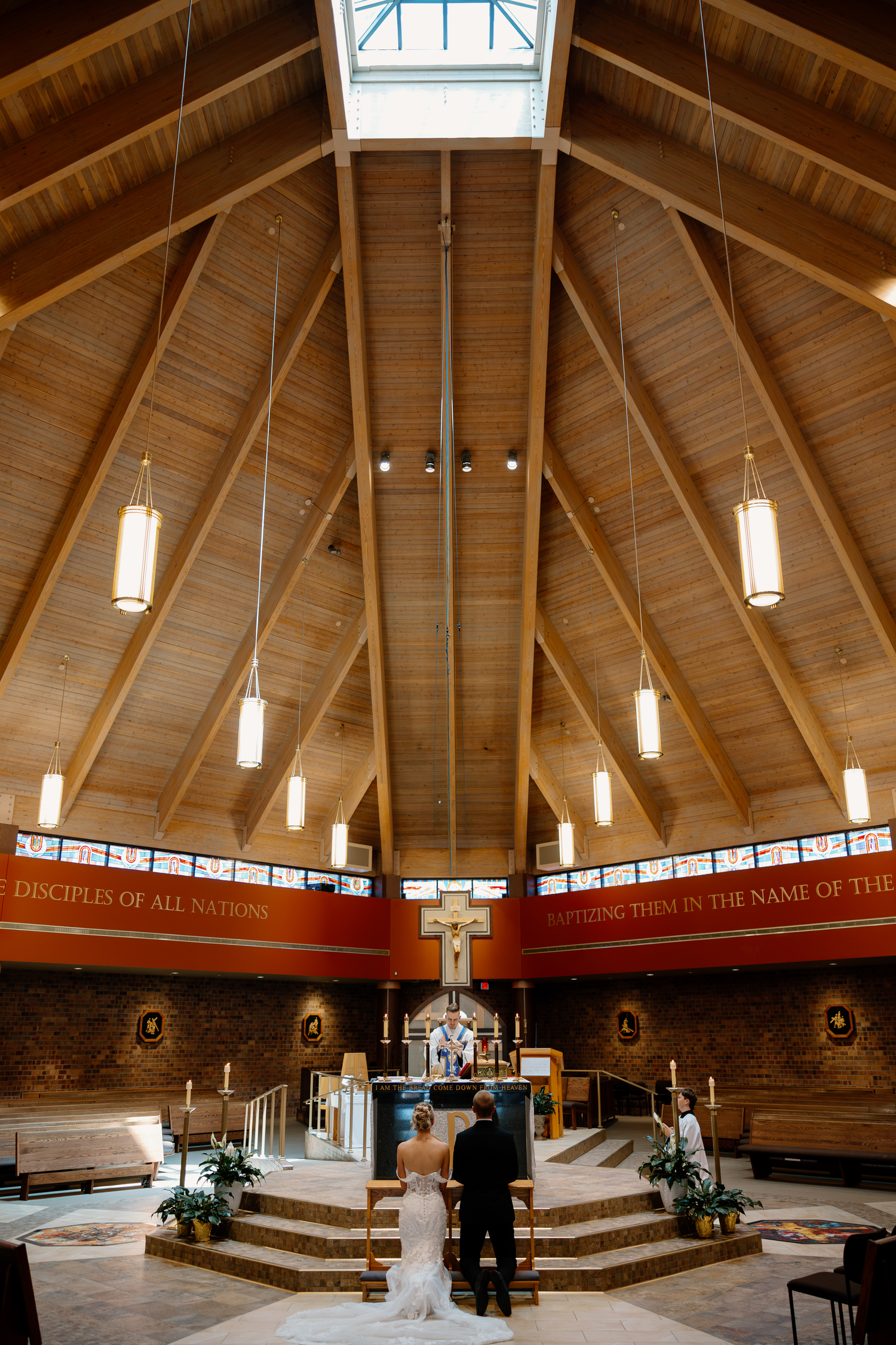 Bride and groom stand at the altar of a stunning wooden cathedral church during their wedding ceremony.
