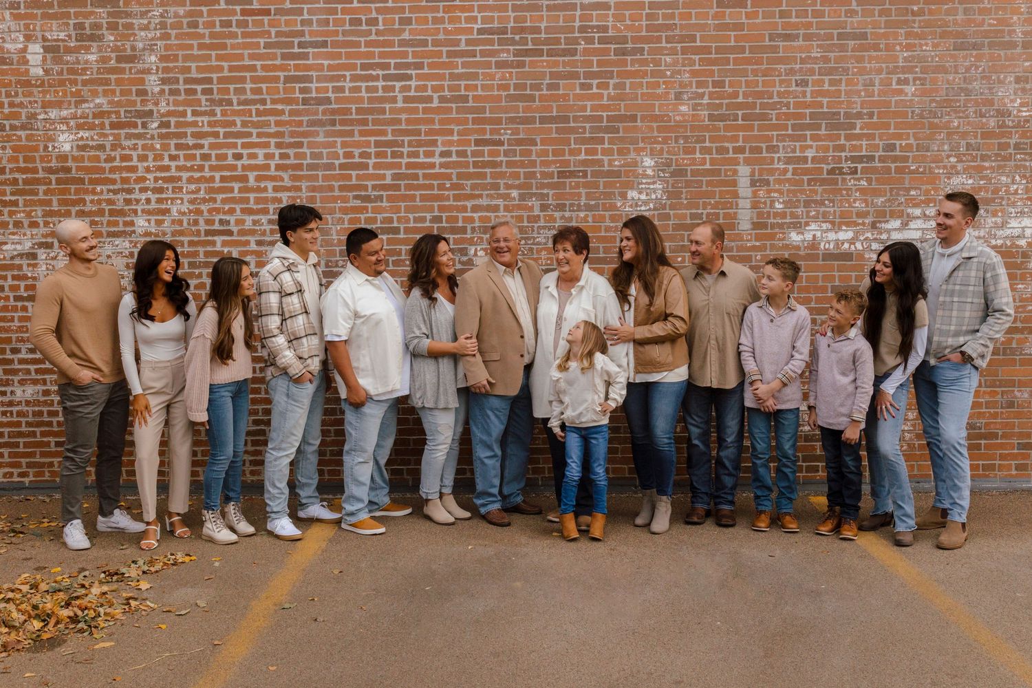 Group of people standing casually against a rustic brick wall wearing light colored clothing for a casual photoshoot.