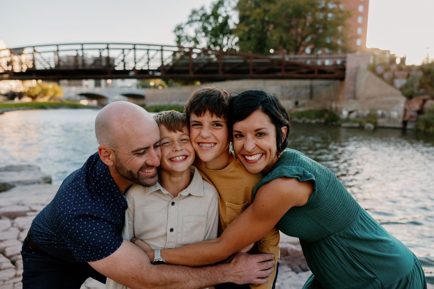 A series of candid family moments captured at sunset by the water showing affectionate embraces and genuine smiles. Riley Ro Photo Sioux Fal