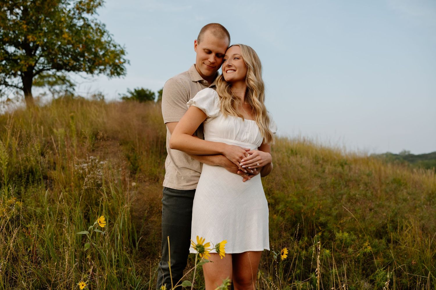 A tender embrace between a couple in a wildflower meadow during golden hour.