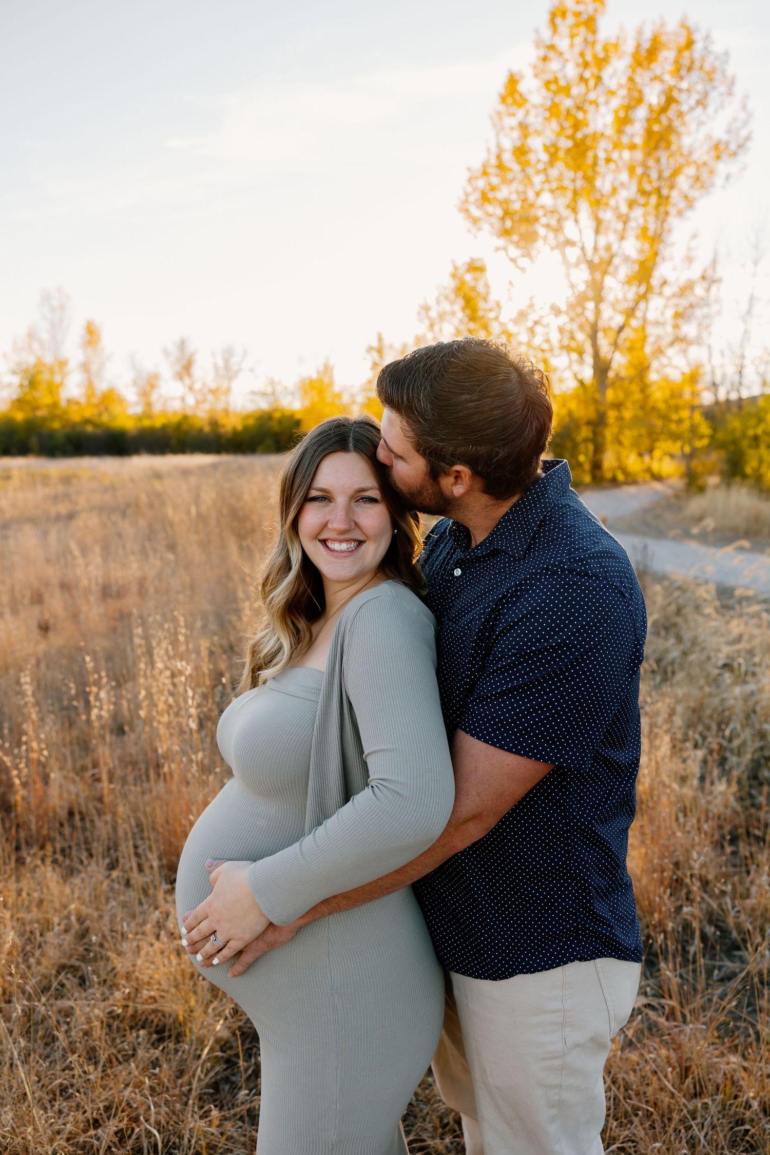 A couple embraces in a sunlit autumn field with golden foliage and warm evening light. Riley Ro Photo Sioux Falls, SD
