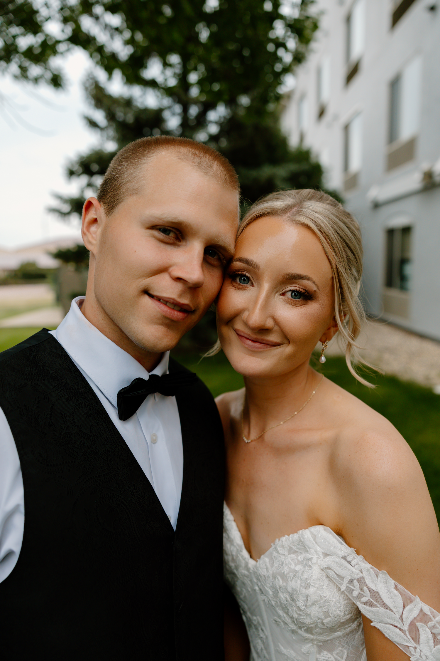 Smiling bride and groom pose cheek to cheek in a romantic close-up wedding portrait outdoors.