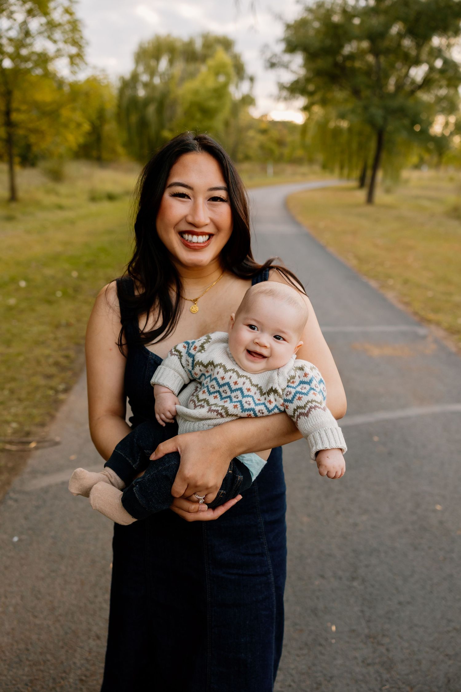 A joyful moment captured between parent and child playing together on a tree-lined path during golden hour.