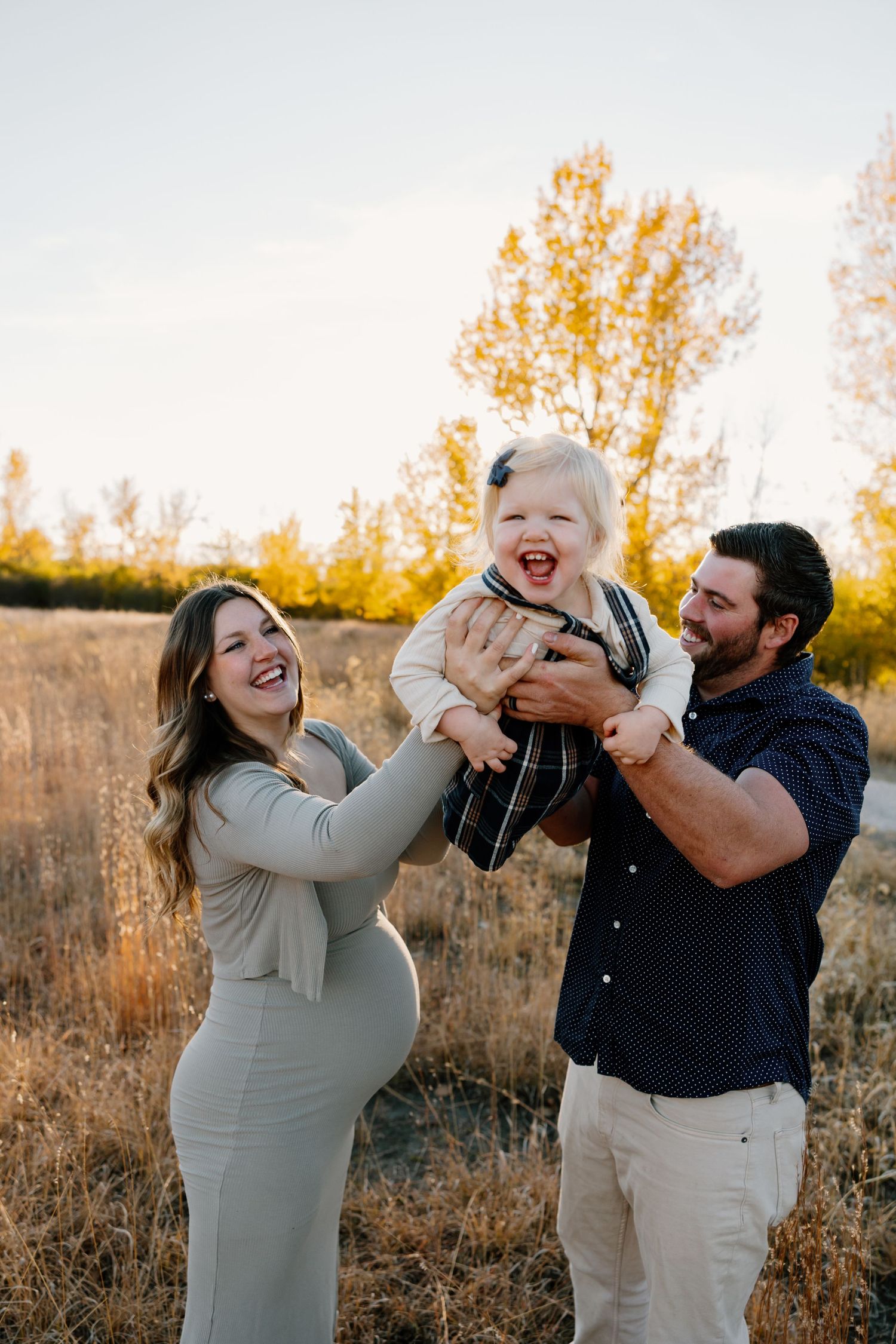 A couple shares playful and candid moments in a golden field during sunset. Riley Ro Photo Sioux Falls, SD