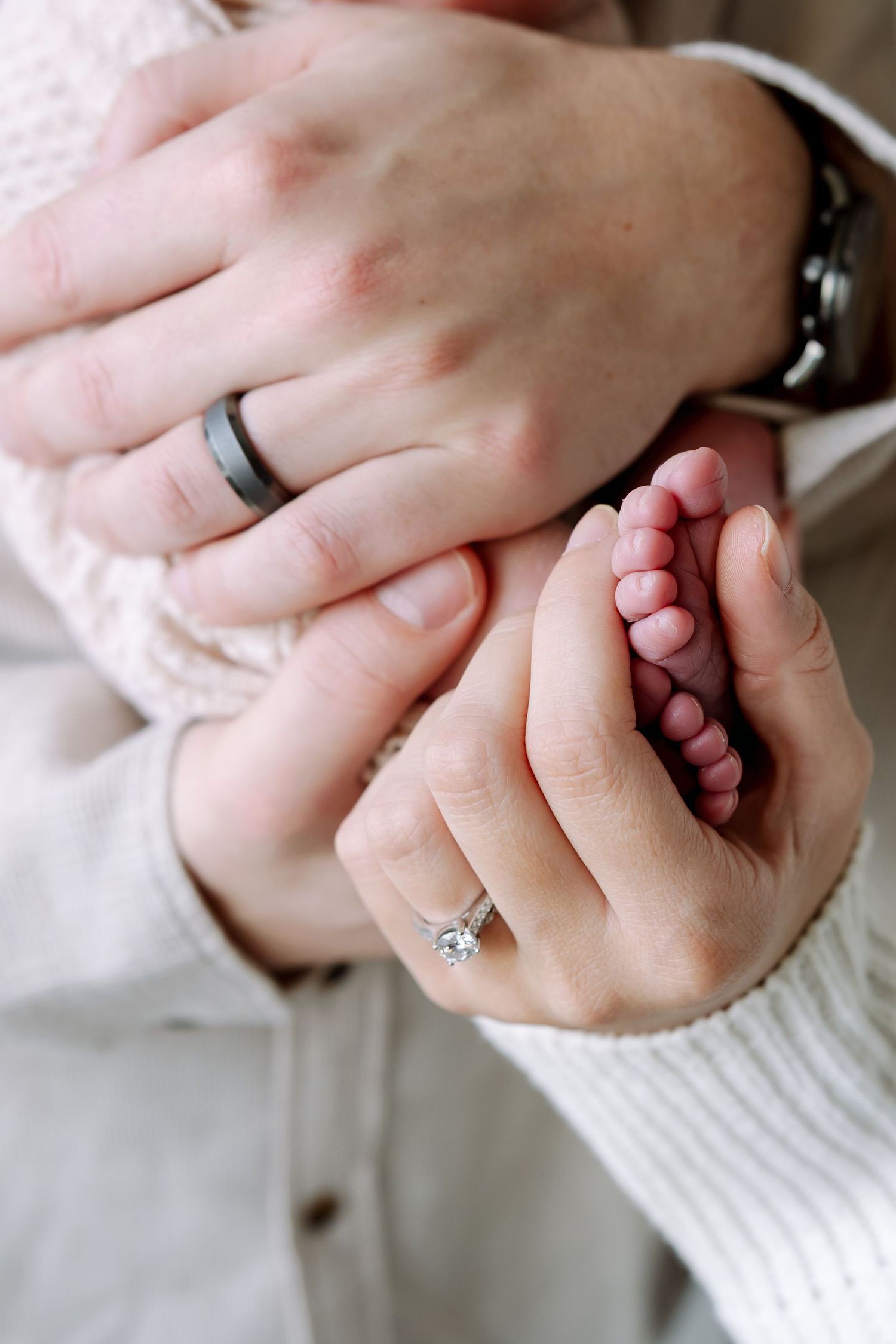 Close-up series of hands holding and interlocking fingers with a diamond engagement ring visible in soft lighting.