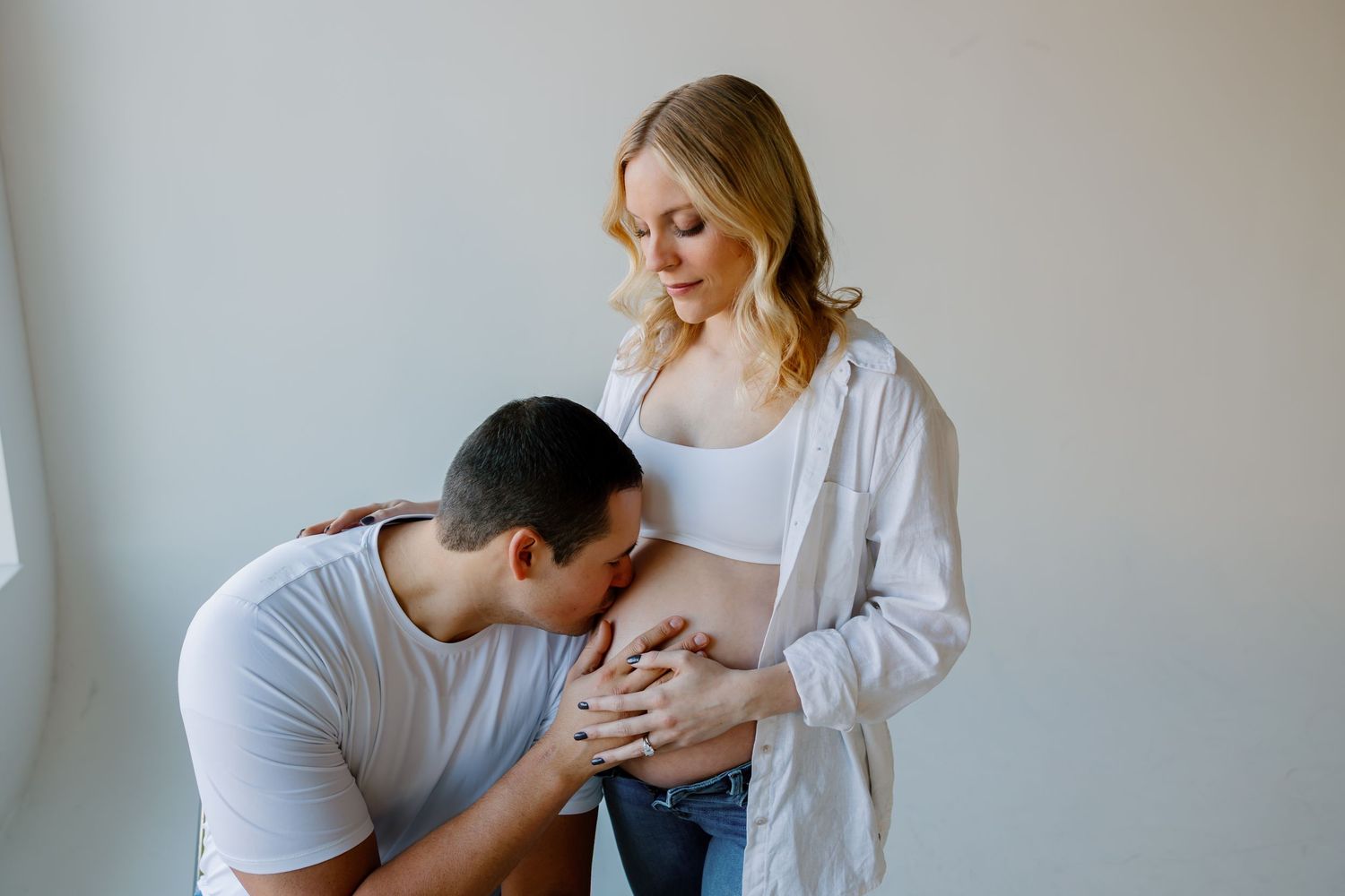 A couple embraces tenderly in a light-filled room while sharing intimate moments together. Riley Ro Photo Sioux Falls, SD