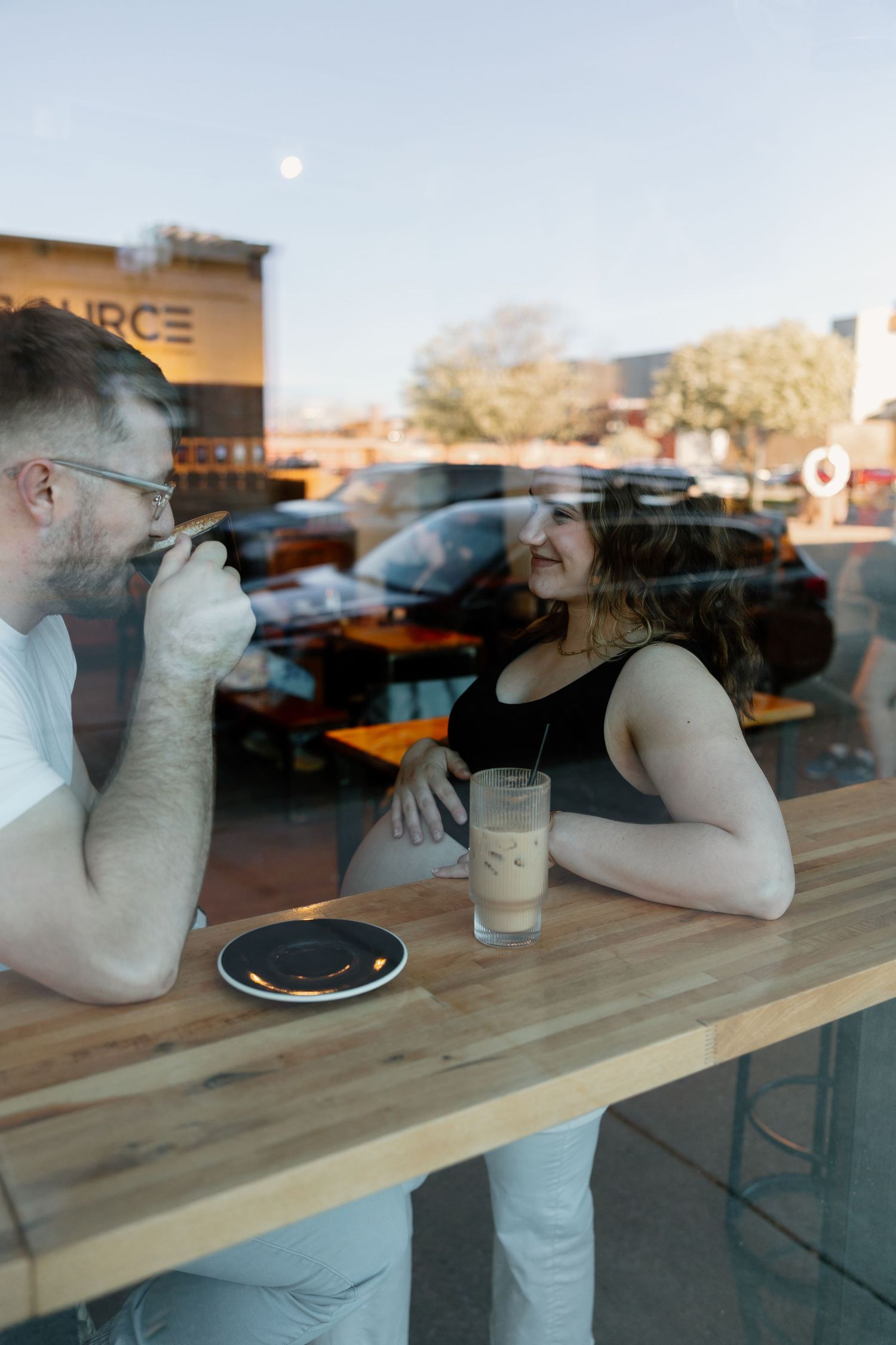 Two people enjoying drinks together at a wooden bar counter seen through a window reflection. Riley Ro Photo Sioux Falls, SD