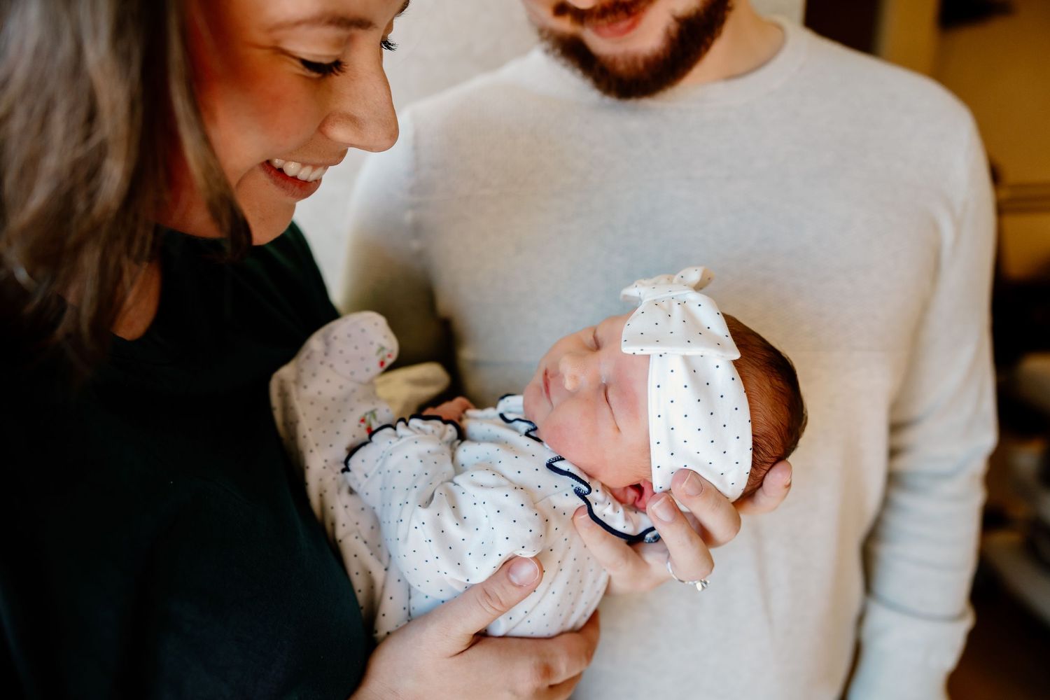 A tender moment showing a parent holding and gazing lovingly at a newborn baby wrapped in white blankets. Riley Ro Photo Sioux Falls, SD