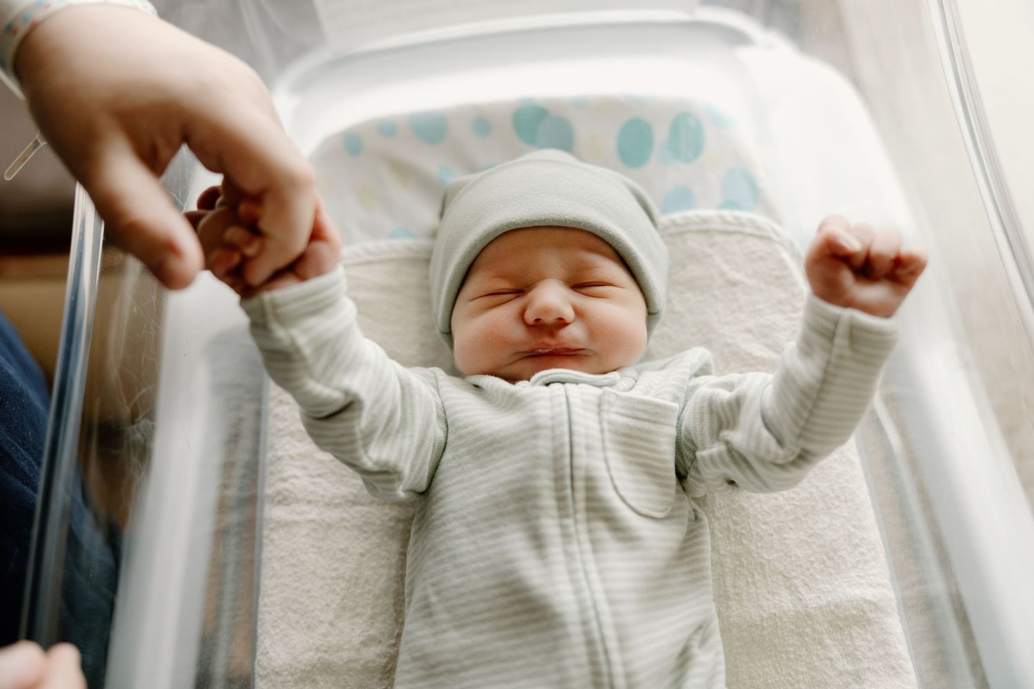 Series of photos showing a baby in white clothing stretching and yawning on a white surface.