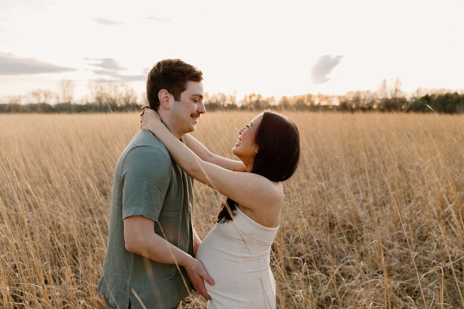 A loving couple shares an intimate moment together in a golden wheat field at sunset.