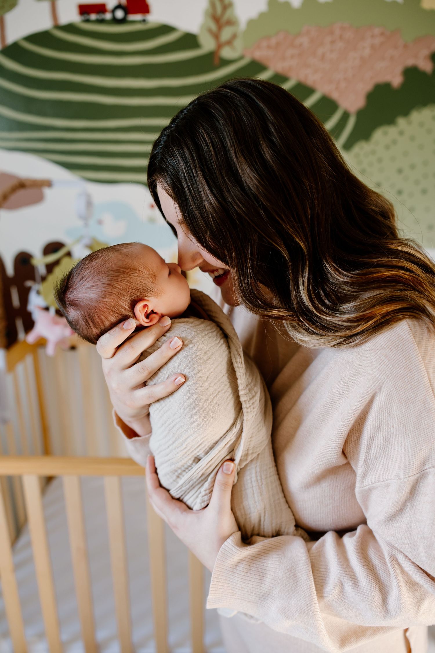 A series of photos showing a tender moment between parent and baby in a nursery with patterned wallpaper.