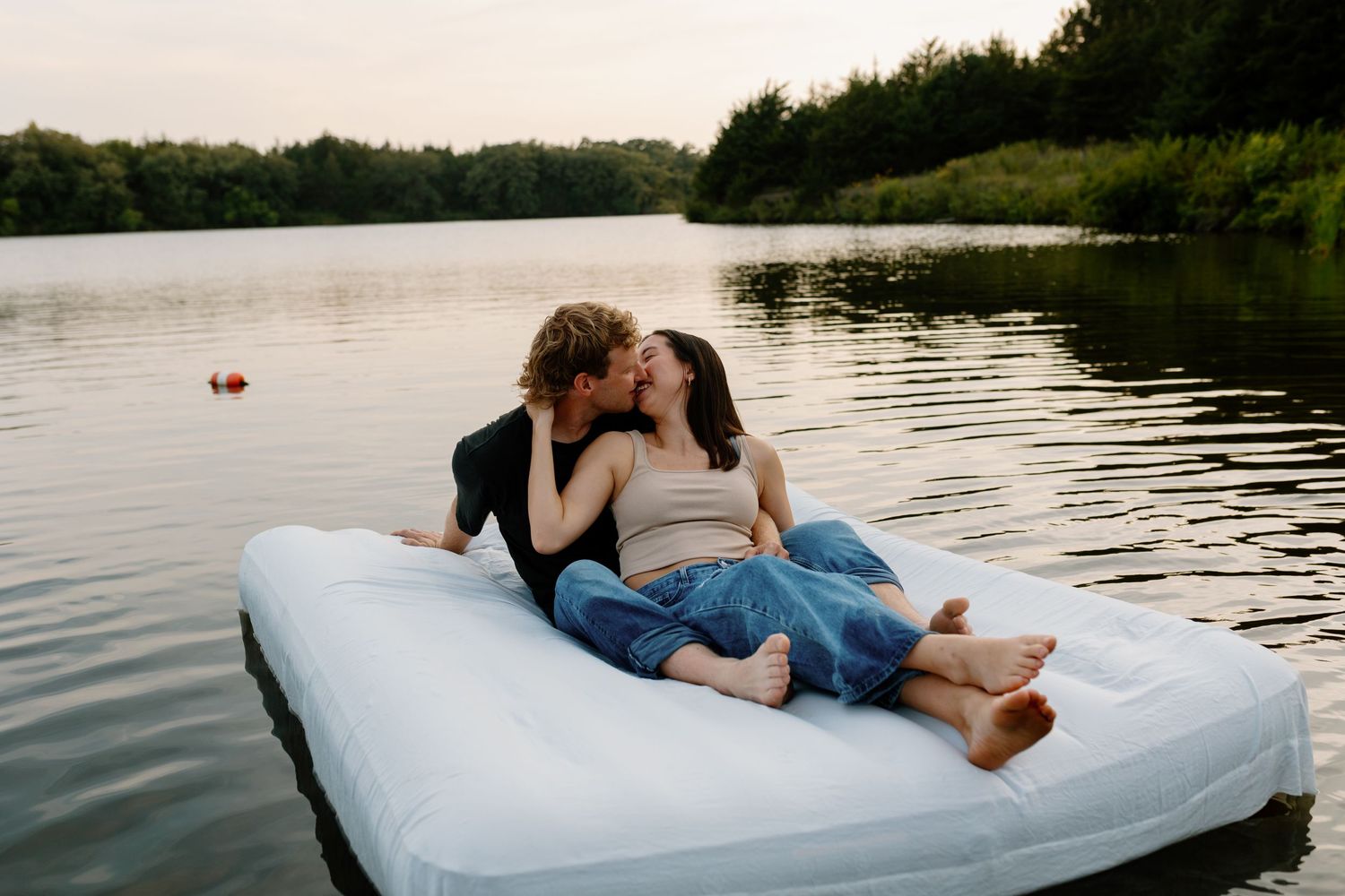 Couple shares intimate moment on floating mattress in tranquil lake setting.

Sioux Falls Photographer  
Evermore Photo Co