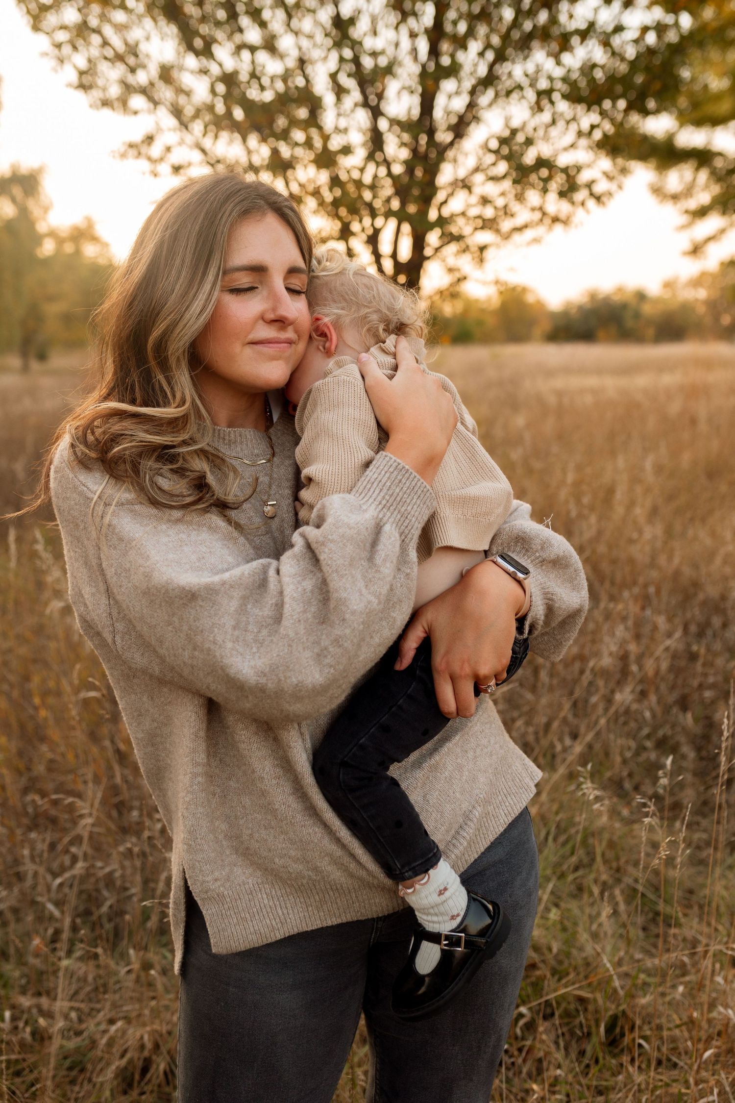 Candid moments captured in a golden field at sunset showing warm embraces and joyful interactions. Riley Ro Photo Sioux Falls, SD