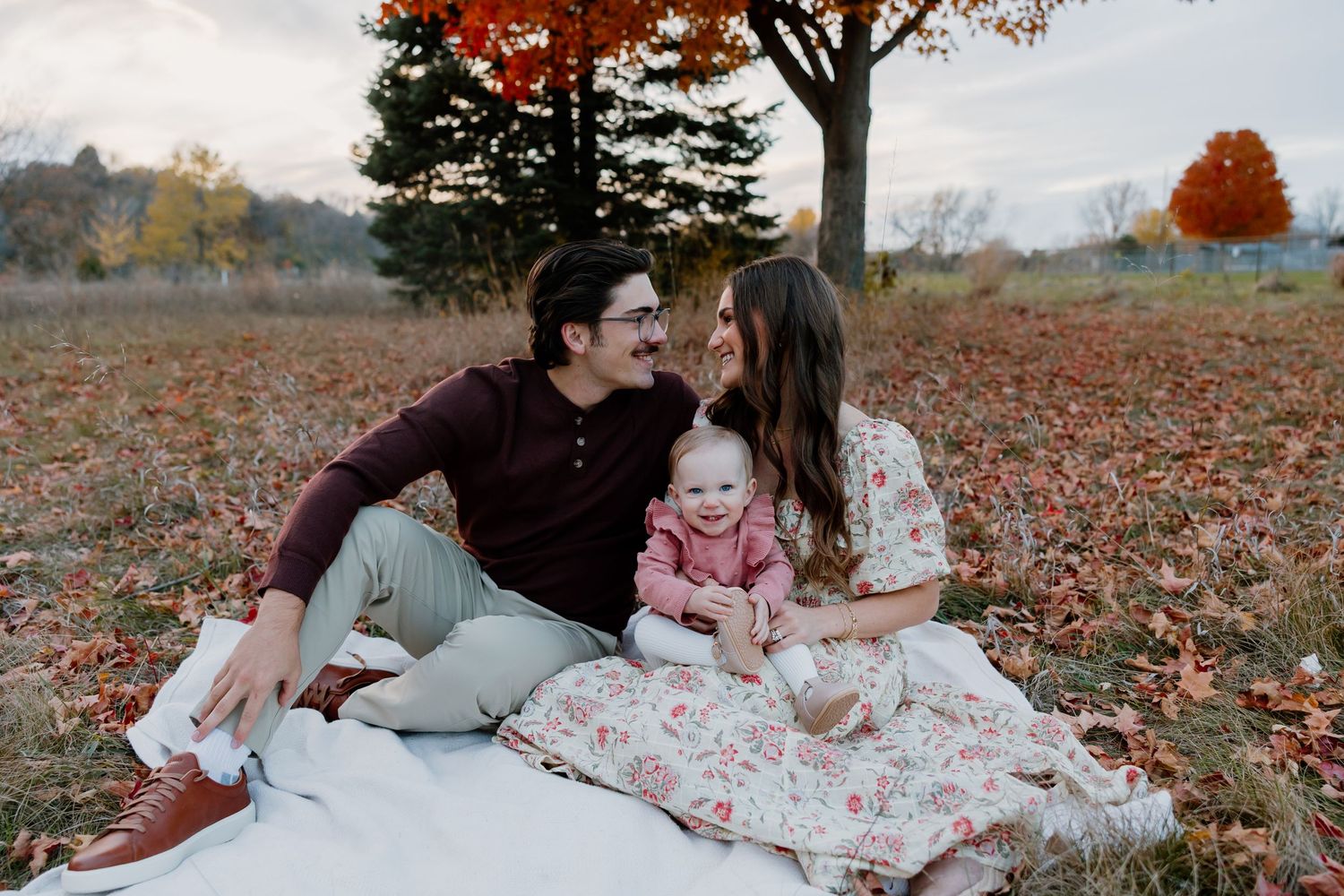 Couple lying on autumn leaves in a park sharing romantic moments during fall season photo shoot.