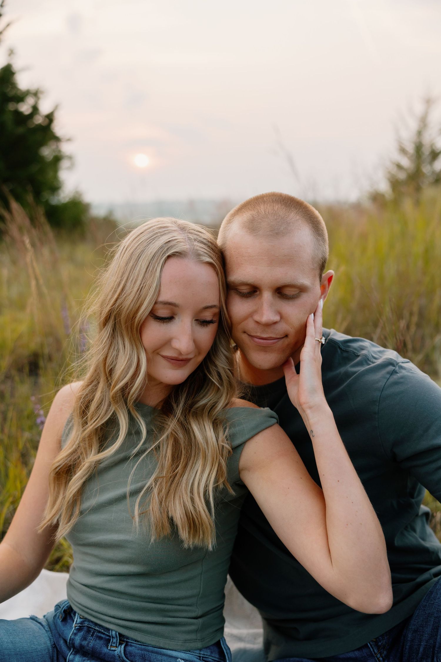 An intimate moment between a couple sitting close together at sunset in a field of tall grass. sioux falls photographer riley ro photo