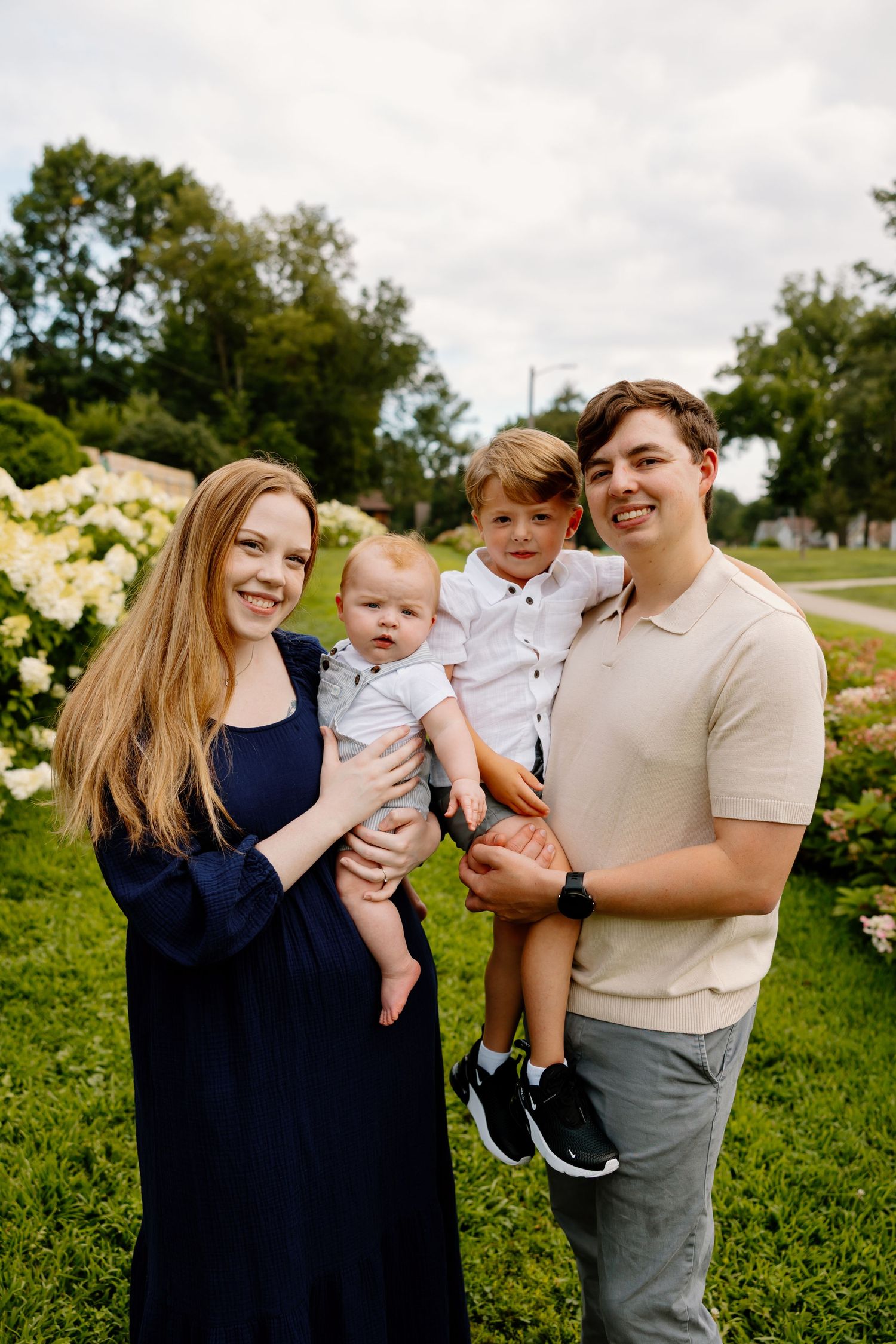 Family enjoying a playful outdoor photo session together in a green field on an overcast day. Riley Ro Photo Sioux Falls, SD
