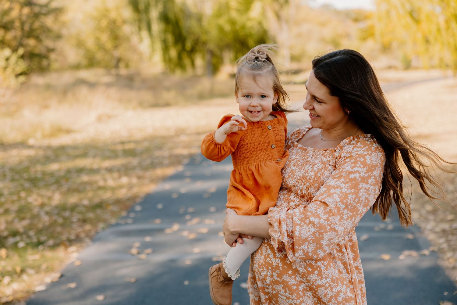 A warm autumn photoshoot outdoors with fall colors and coordinated orange and white outfits.
