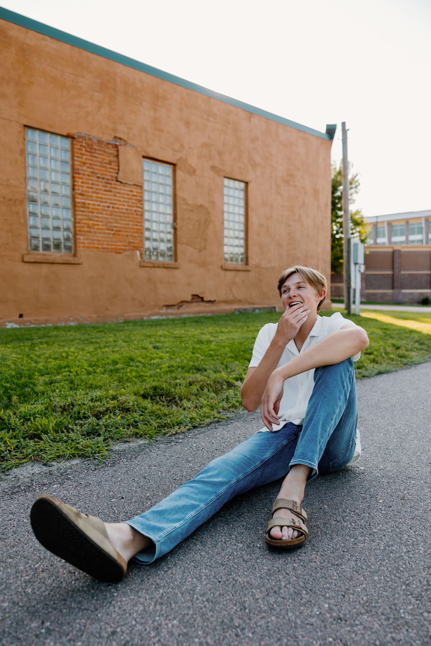A relaxed portrait session showing someone sitting on pavement near a brick building.
