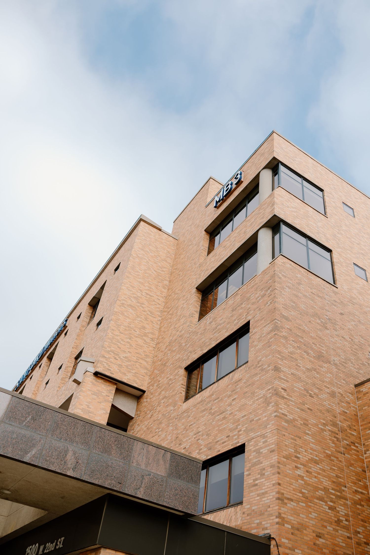 Modern brick apartment building with geometric angles photographed against blue sky.